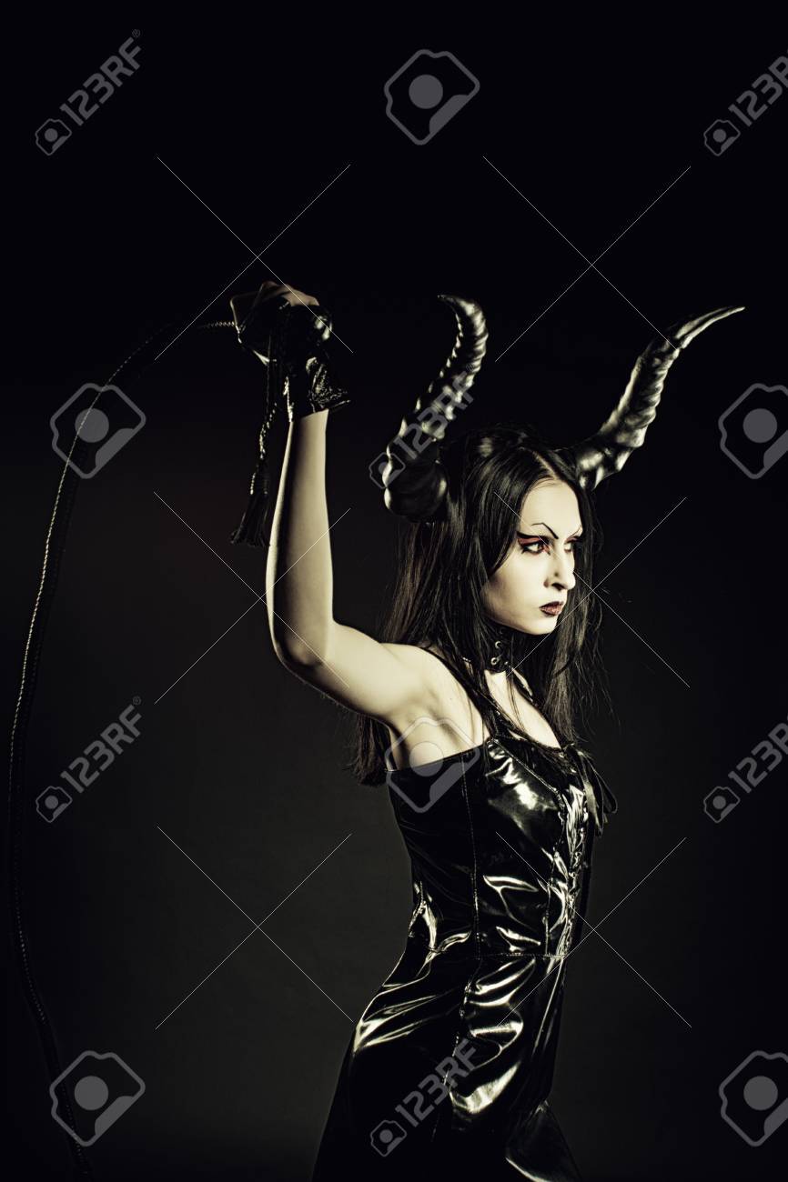 Seductive Horned Mistress With Whip Posing Over Dark Background