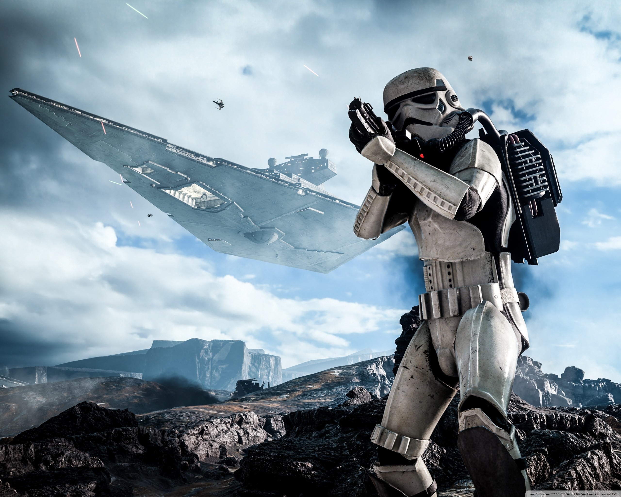 A stormtrooper from Star Wars stands in a rocky landscape with a Star Destroyer in the background