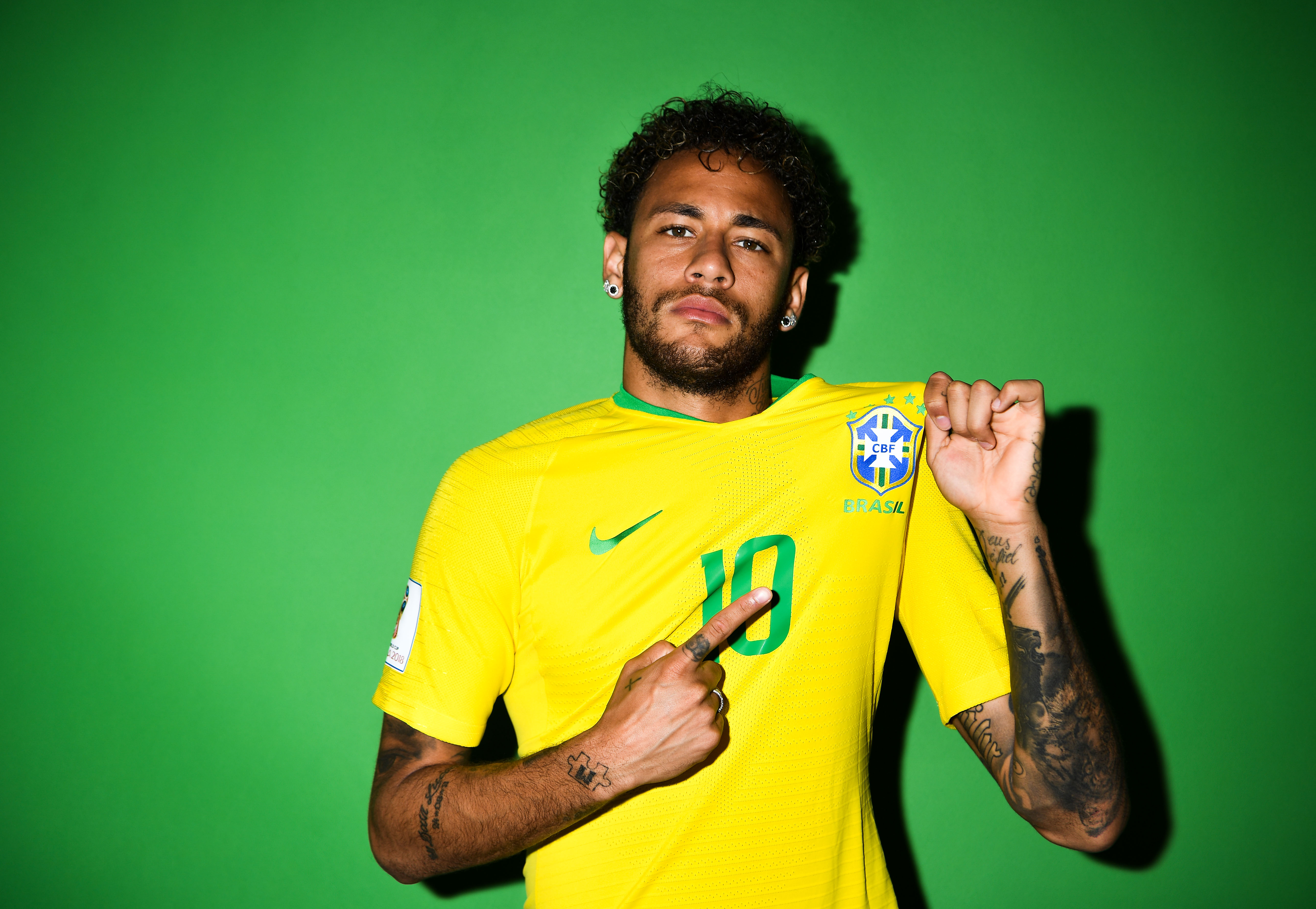 Neymar Jr. posing in his Brazil national team jersey against a green background
