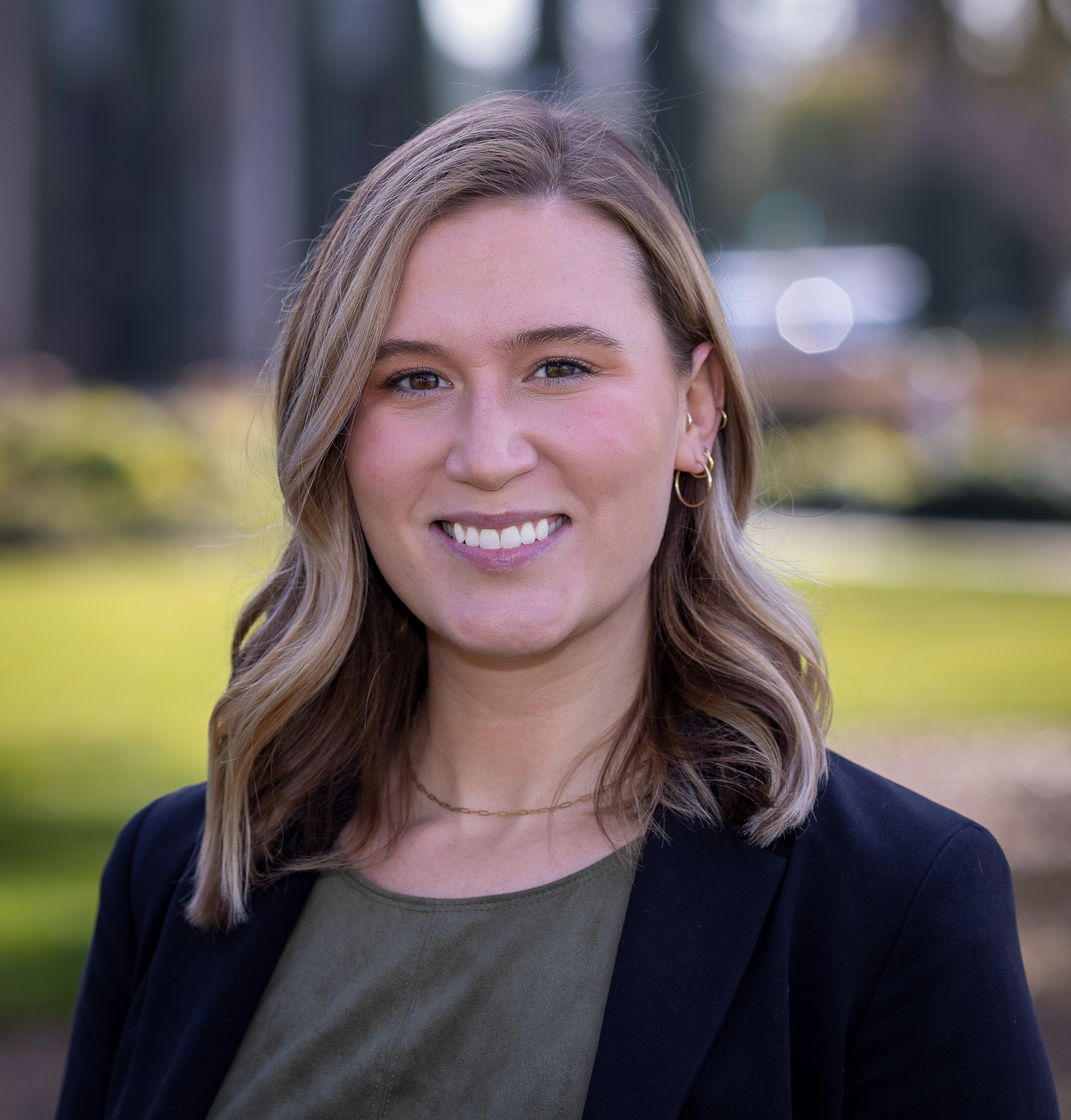 Emily Armstrong smiling outdoors, wearing a green shirt and a black blazer