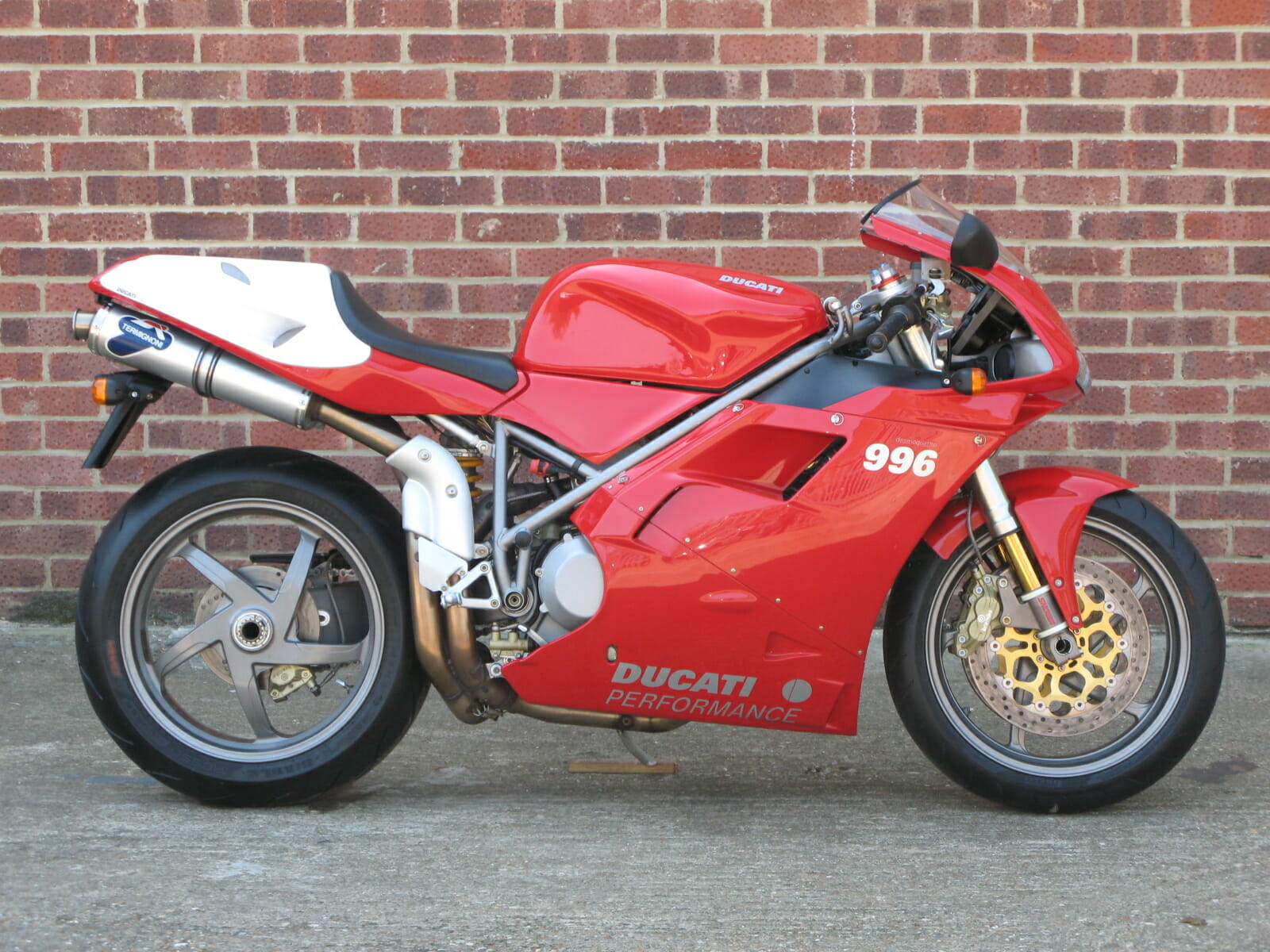 A Ducati 996 sportbike parked against a brick wall