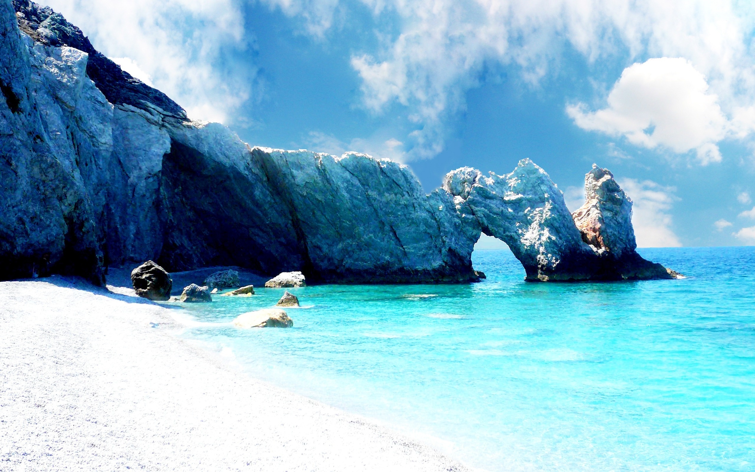 A breathtaking view of Lalaria Beach in Skiathos, Greece, with crystal clear turquoise waters, white pebble beach, and a natural rock arch