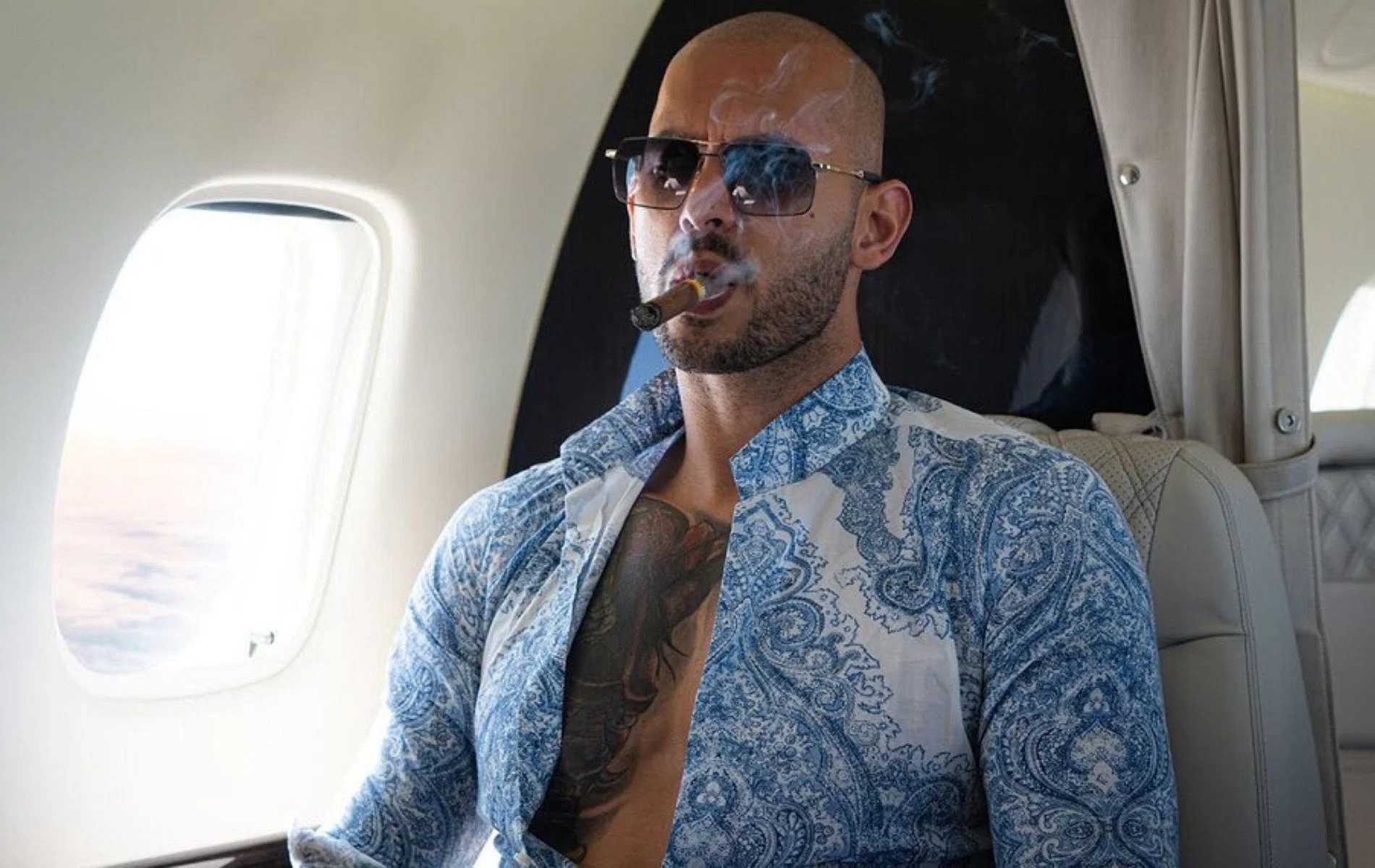 Andrew Tate enjoys a cigar on a private jet, exuding an aura of luxury and success