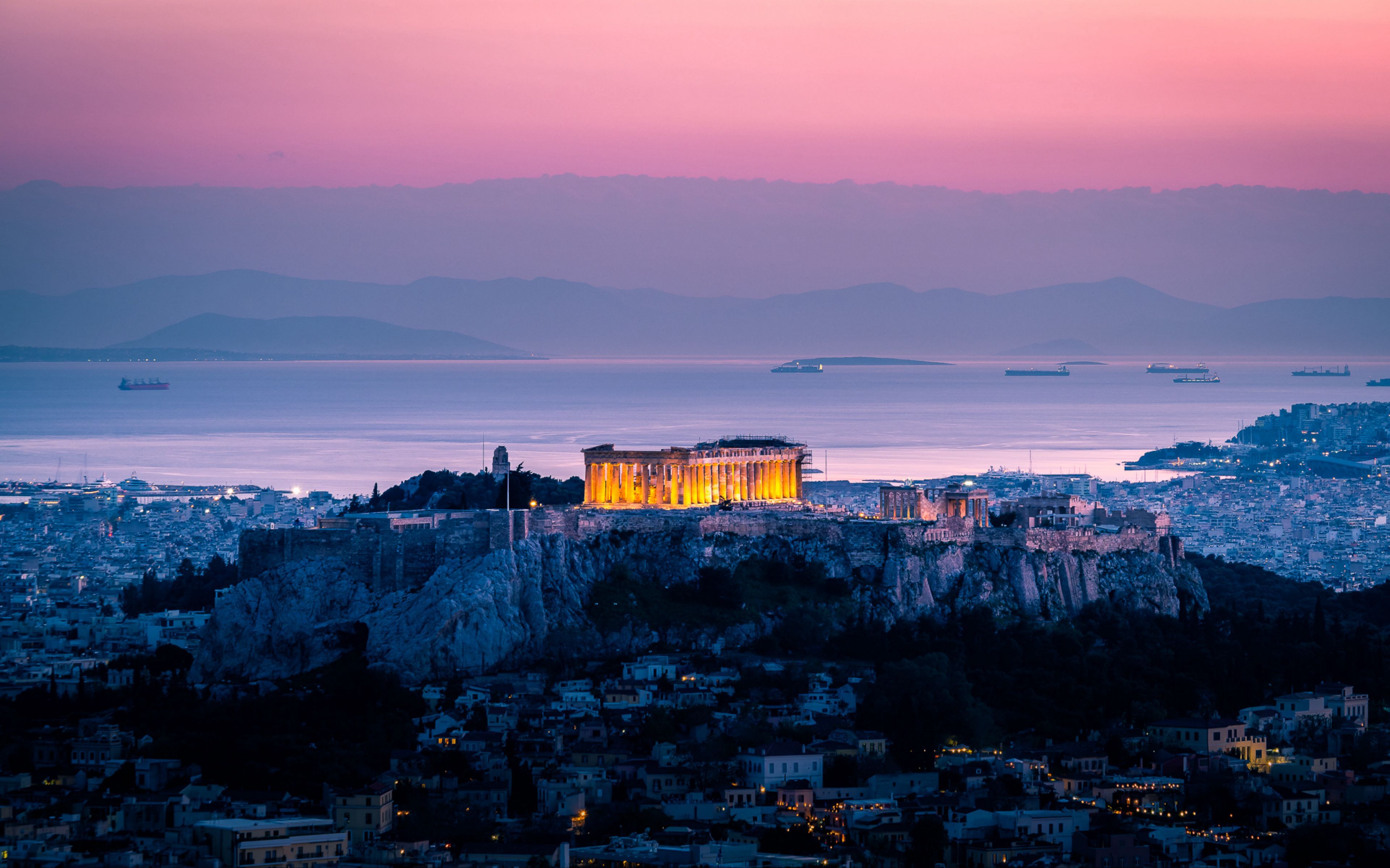 The Acropolis of Athens illuminated at sunset, overlooking the city and the Aegean Sea in Greece
