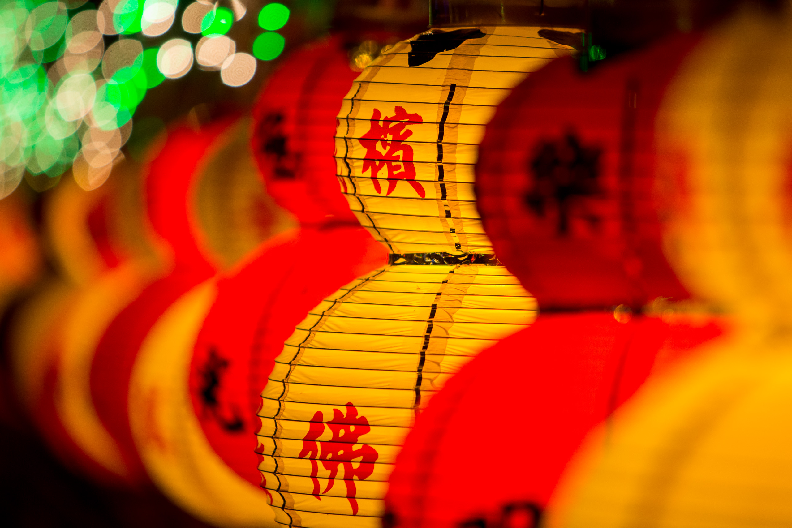 Close-up of vibrant yellow and red Chinese lanterns with Chinese characters, possibly during a festival