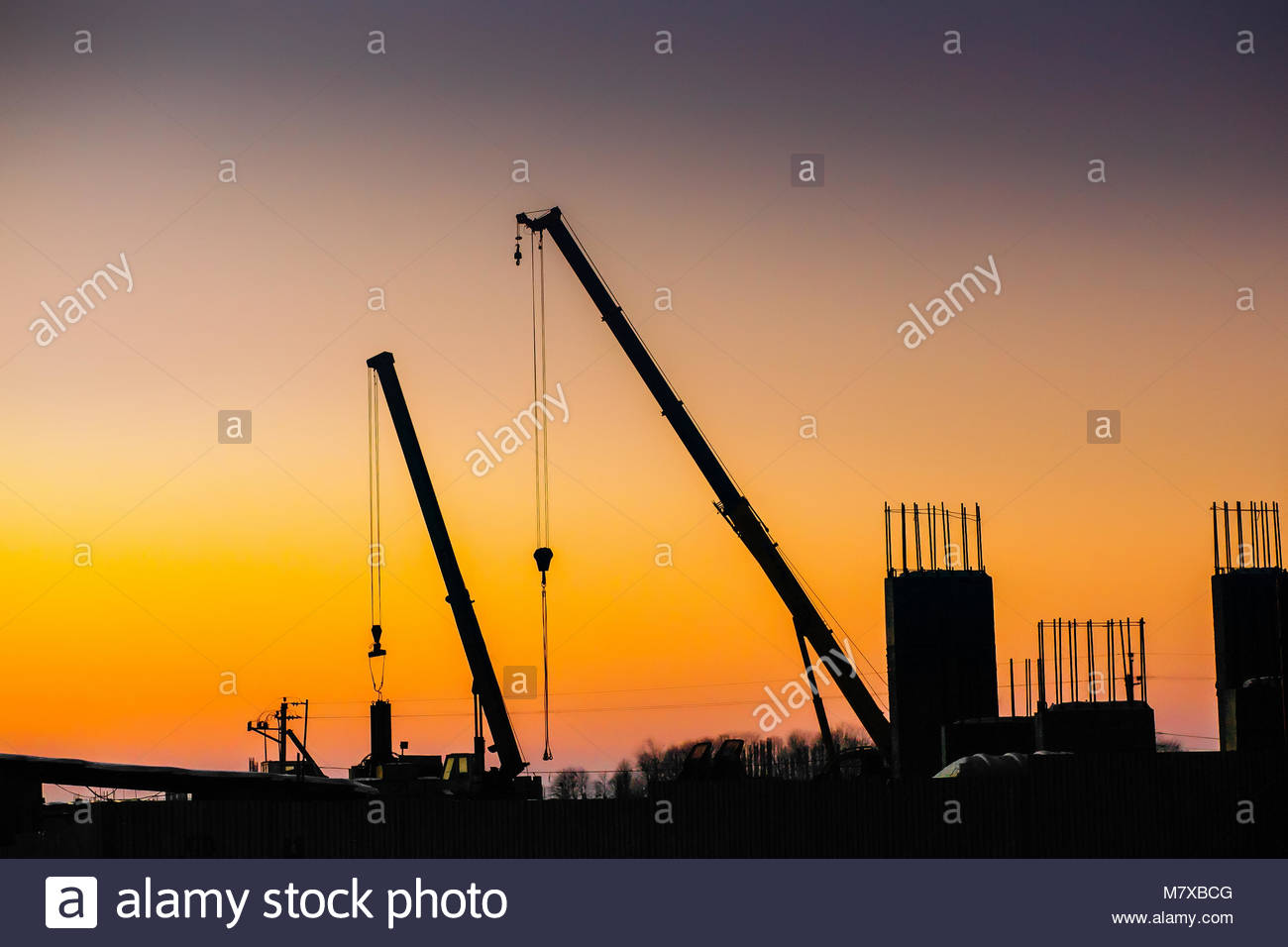 Crane And Building Construction Site On Background Of Sunset Sky