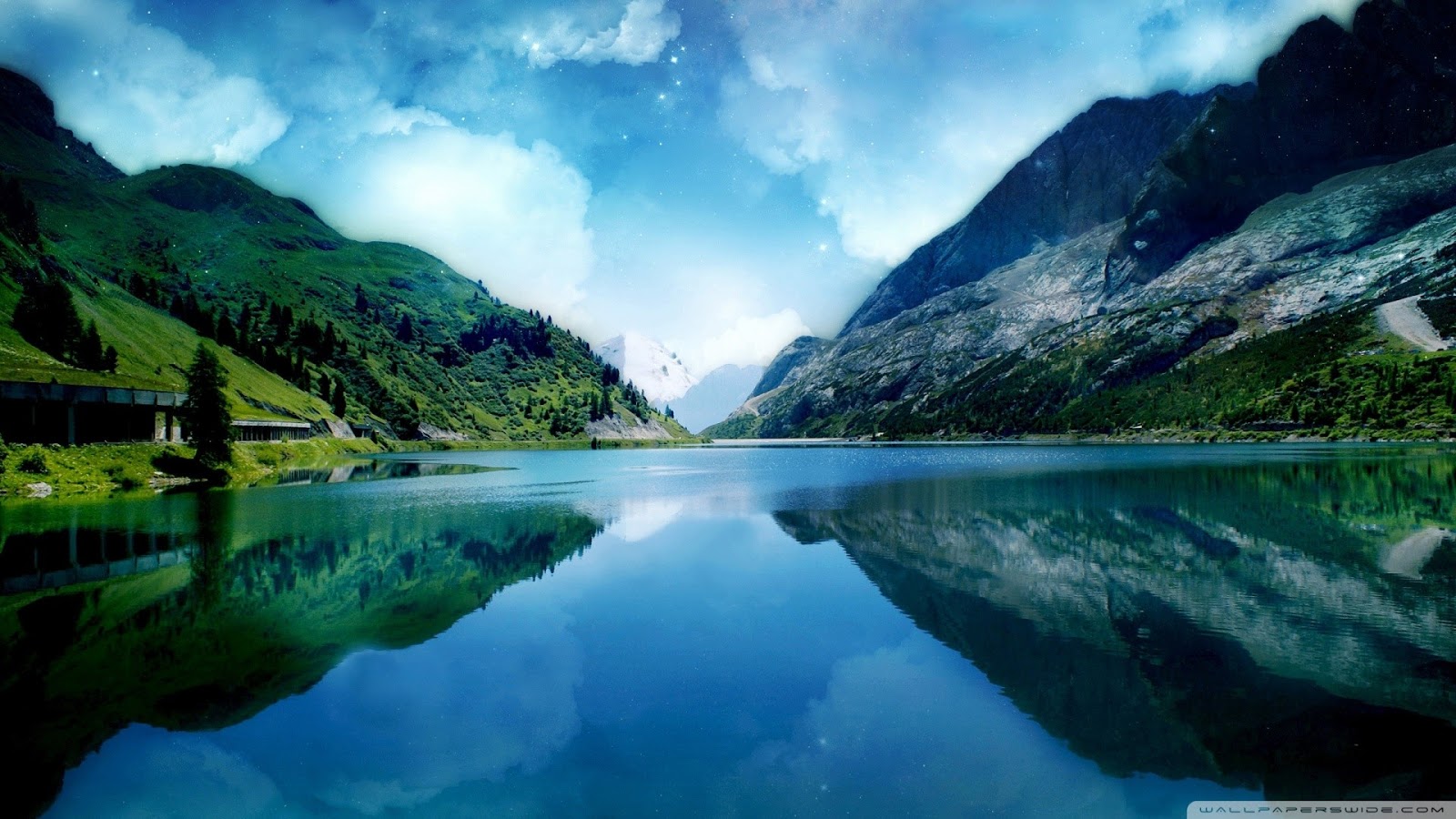 A serene lake reflects the surrounding mountains and sky, creating a breathtaking natural landscape