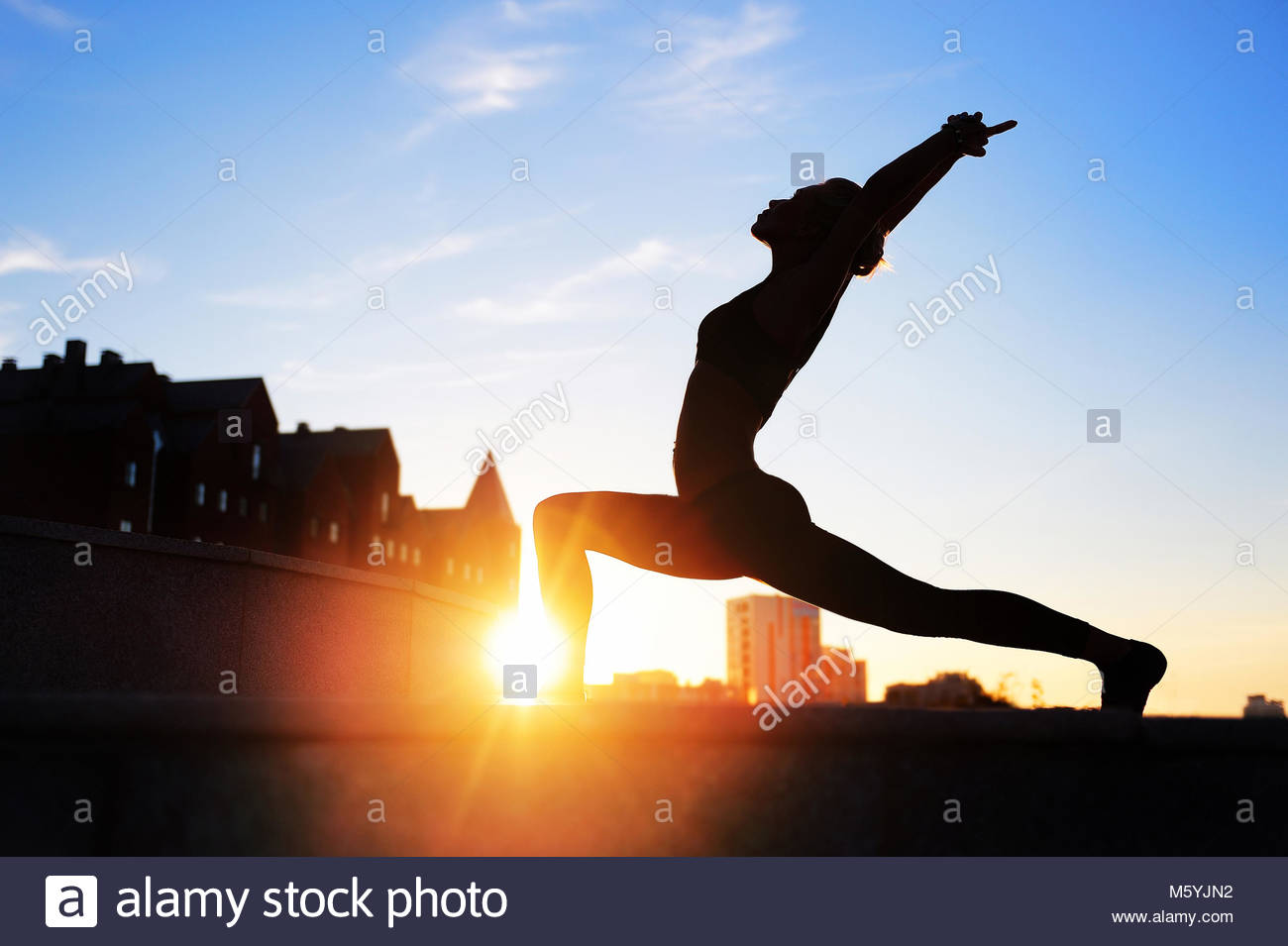 A yoga woman silhouette performing warrior pose on a dark colourful  background with a glare Stock Photo - Alamy