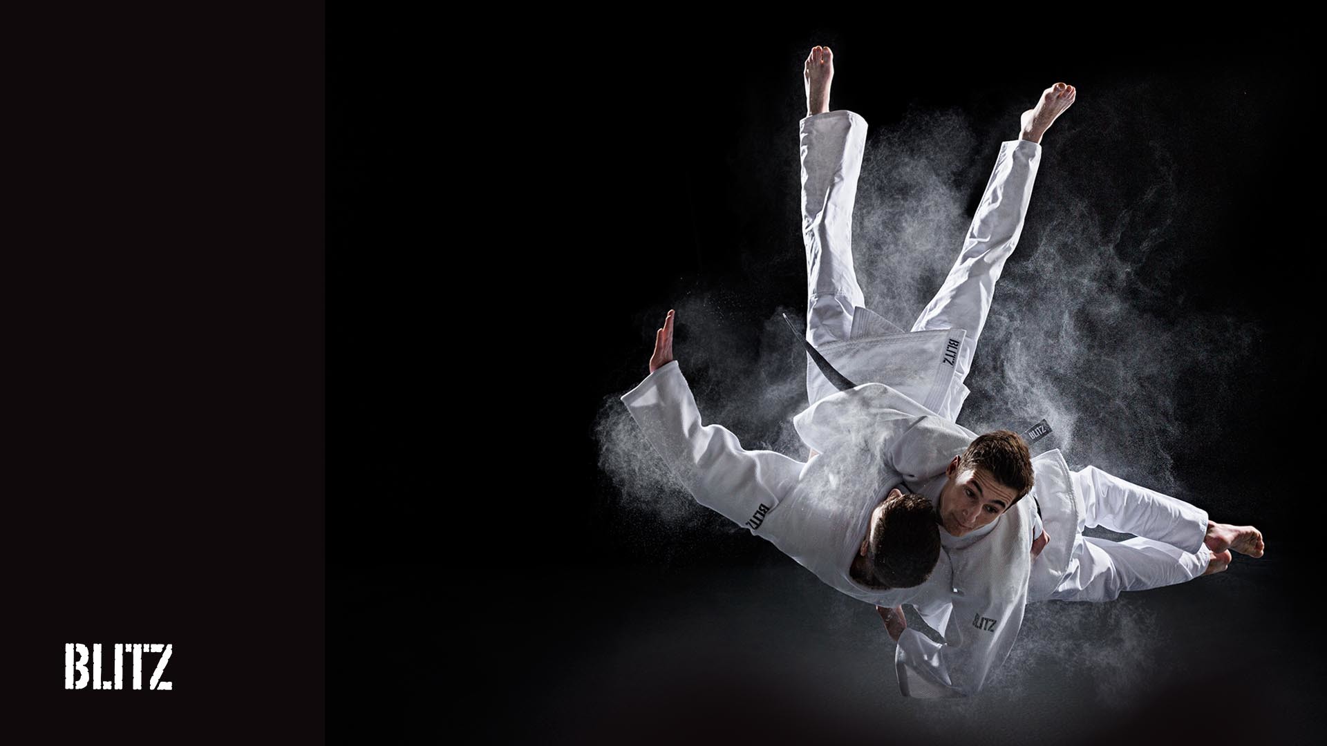 Two judokas in mid-air, executing a dynamic throw, surrounded by a cloud of white powder against a black background