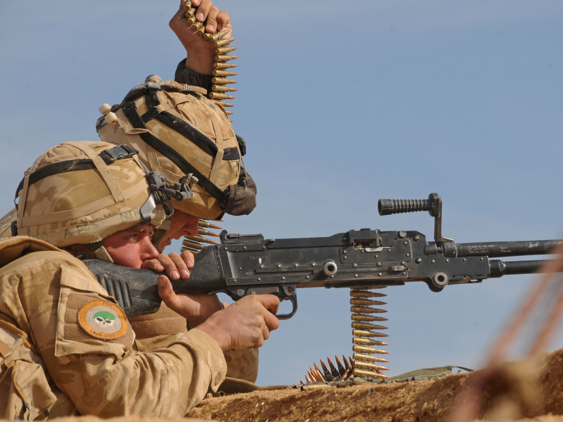 Two French Commandos Marine soldiers in desert camouflage operating a machine gun, with one soldier holding a belt of ammunition