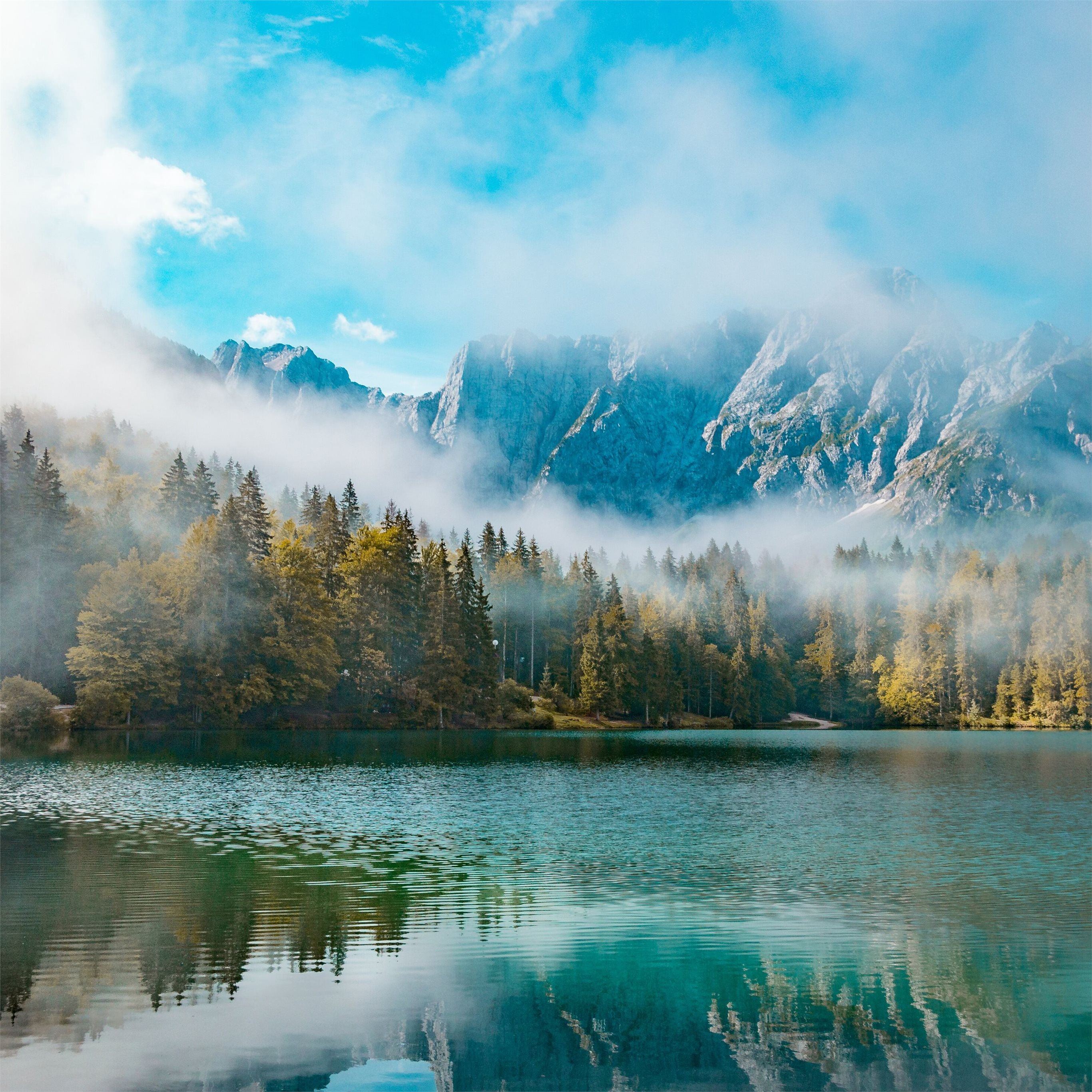 A breathtaking 4K wallpaper for iPad featuring a serene lake reflecting the majestic peaks of a misty mountain range, creating a tranquil and awe-inspiring scene