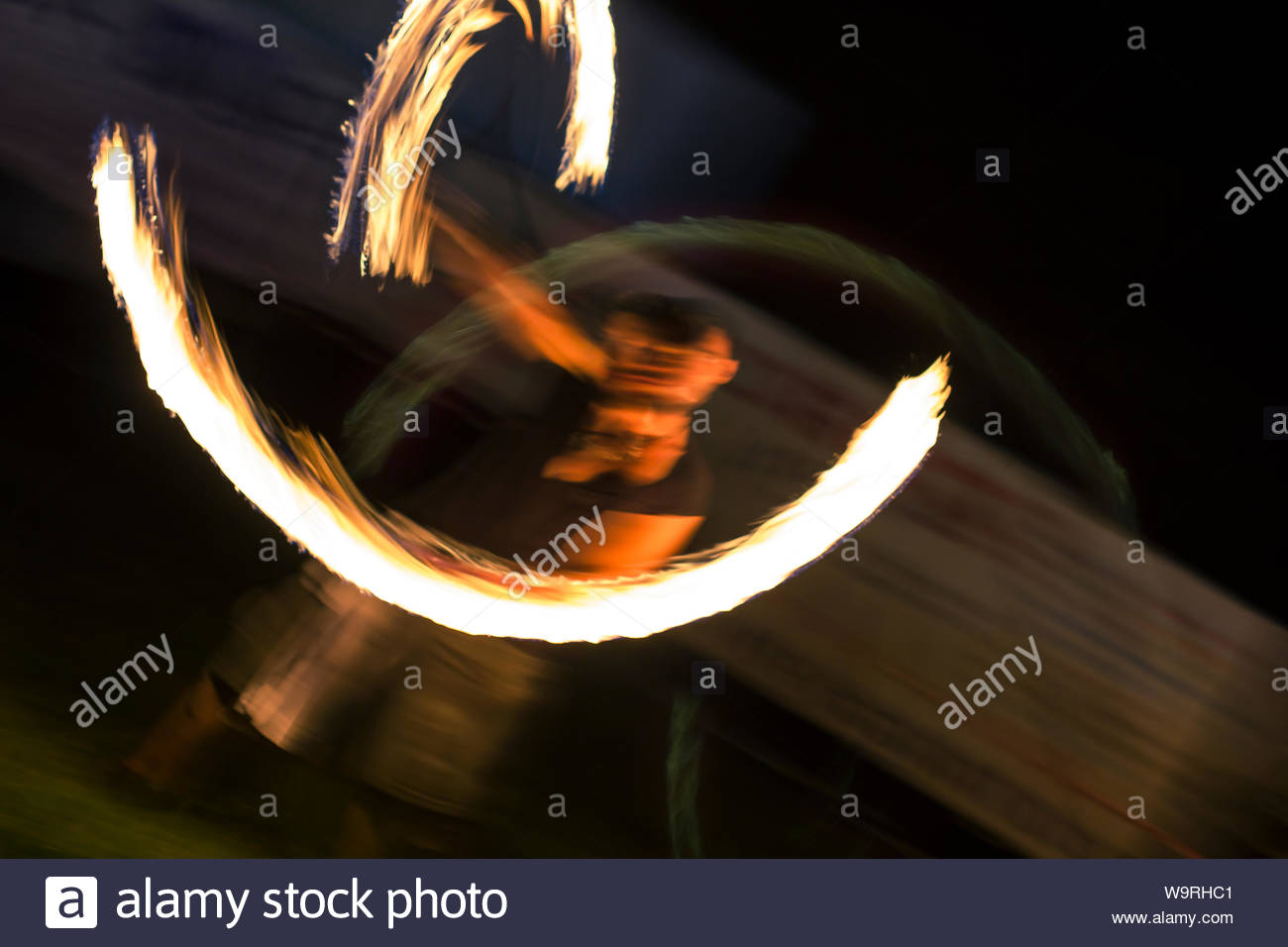Motion blurred night shot showing a fire eater jugglers torches