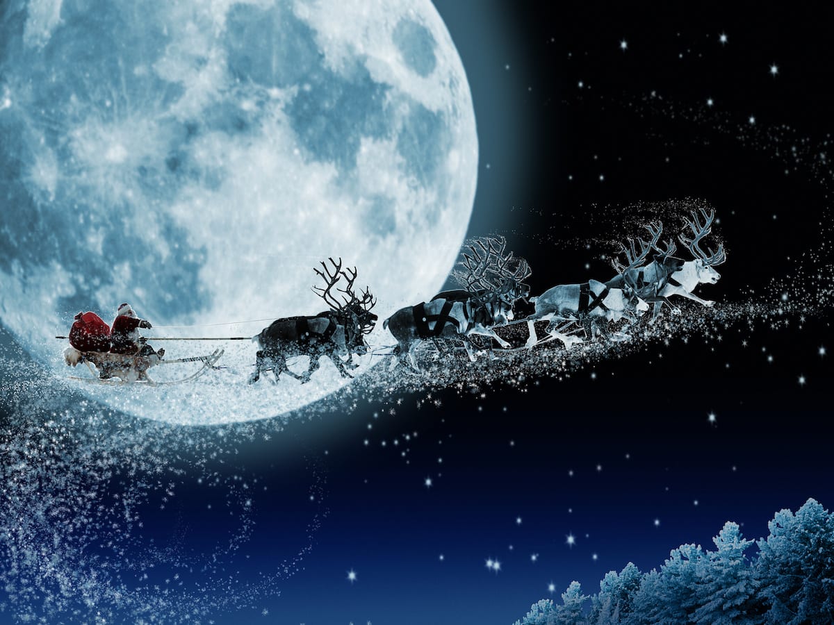 Santa Claus flying his sleigh with reindeer against a bright full moon in a starry night sky, a perfect Christmas wallpaper