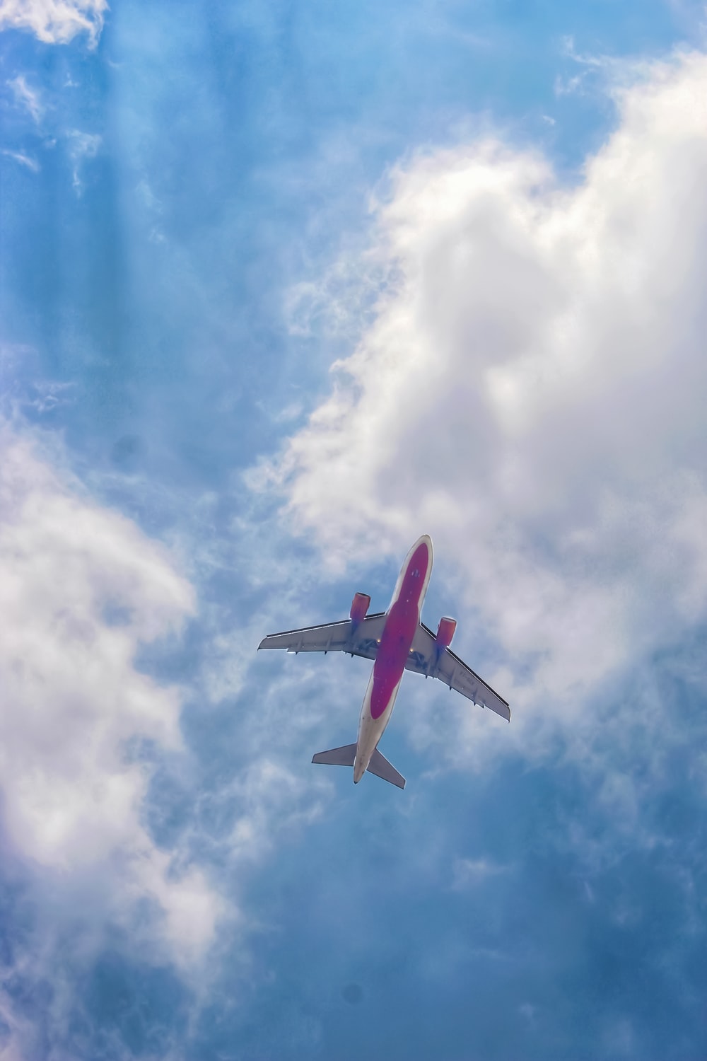 Red And White Airplane Under Blue Sky Clouds During
