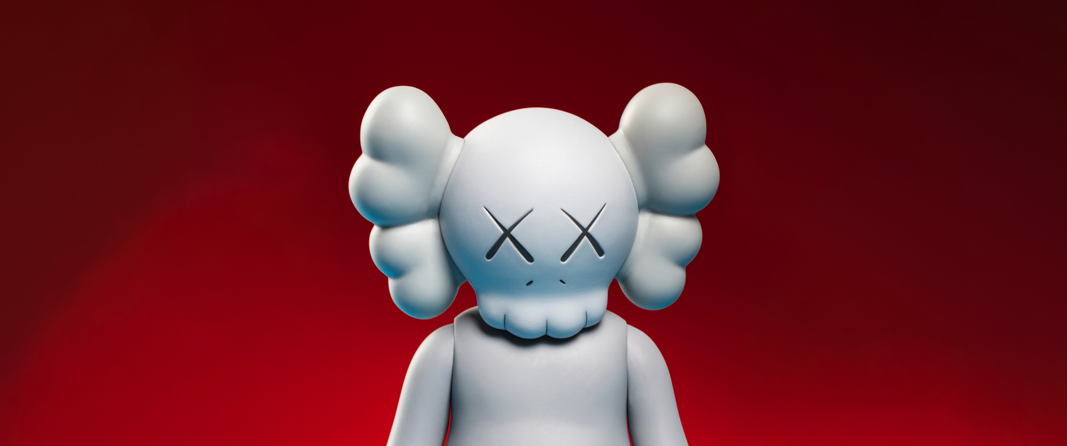 Close-up of a Kaws Companion figure against a red background