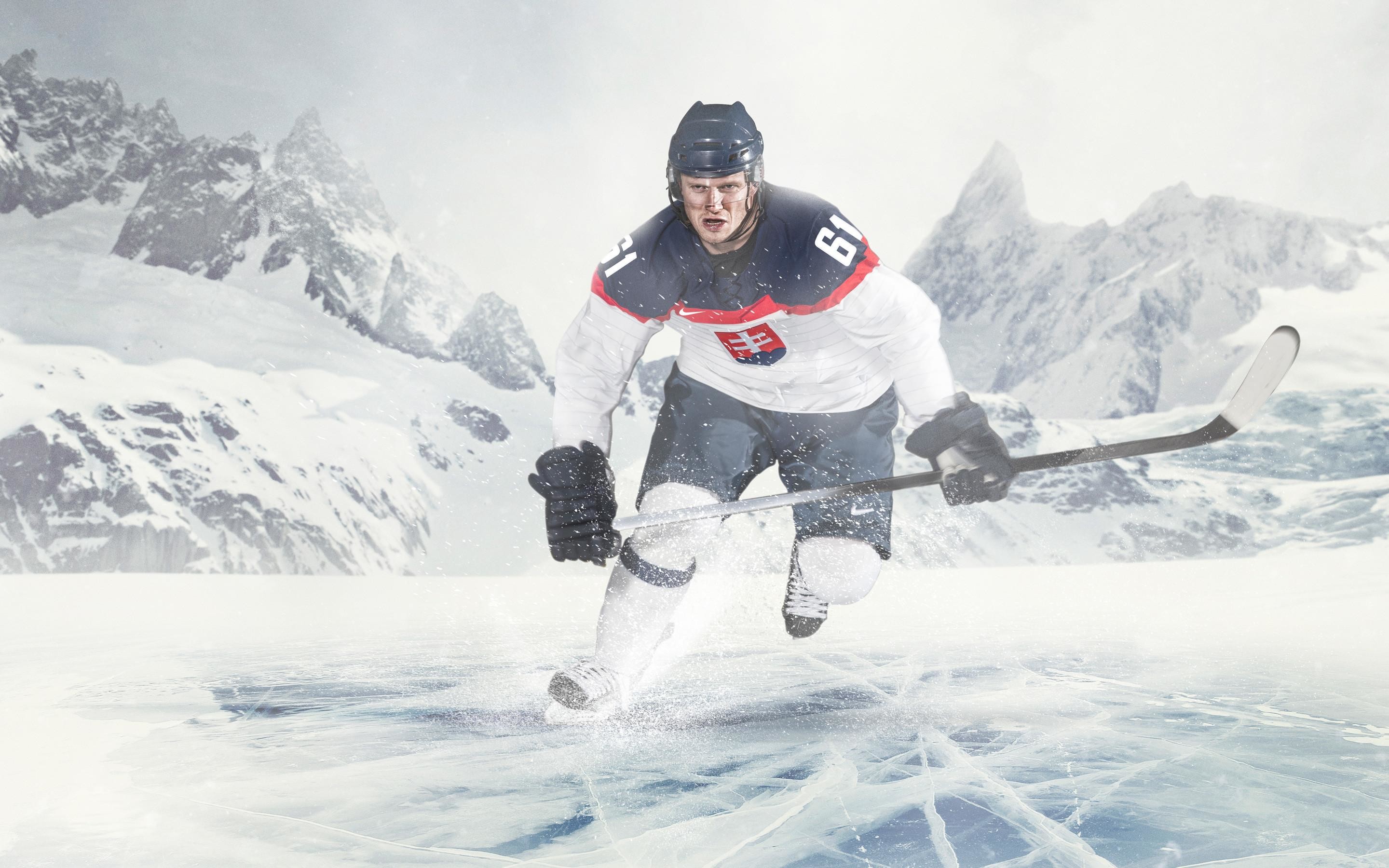 A hockey player in a white and blue jersey with the Slovakian coat of arms skates across a frozen lake with snowy mountains in the background