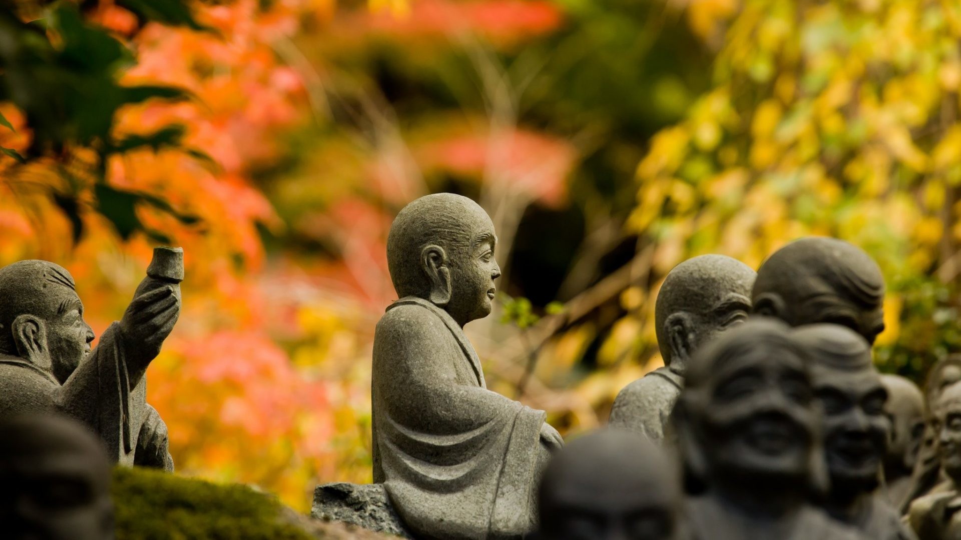 Serene statues of Jizo Bosatsu amidst autumn foliage in a Japanese temple garden