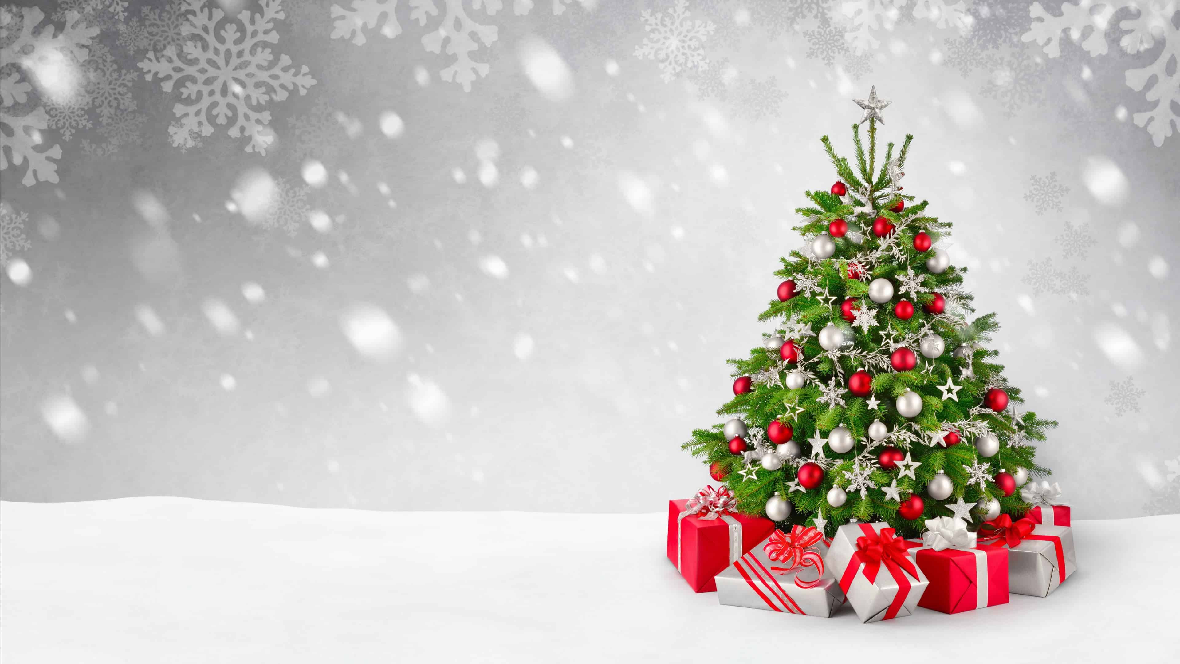 Christmas tree decorated with red and silver ornaments, star topper, and gifts underneath on a snowy background with snowflakes