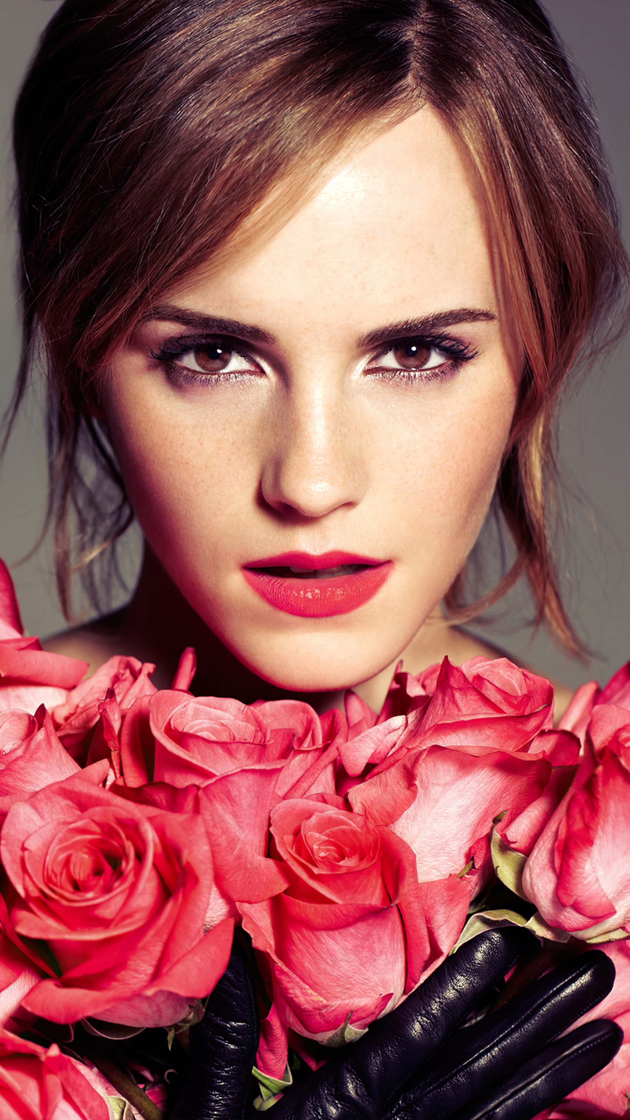 Close-up of a woman holding a bouquet of pink roses, with a focus on her face and the vibrant color of the flowers