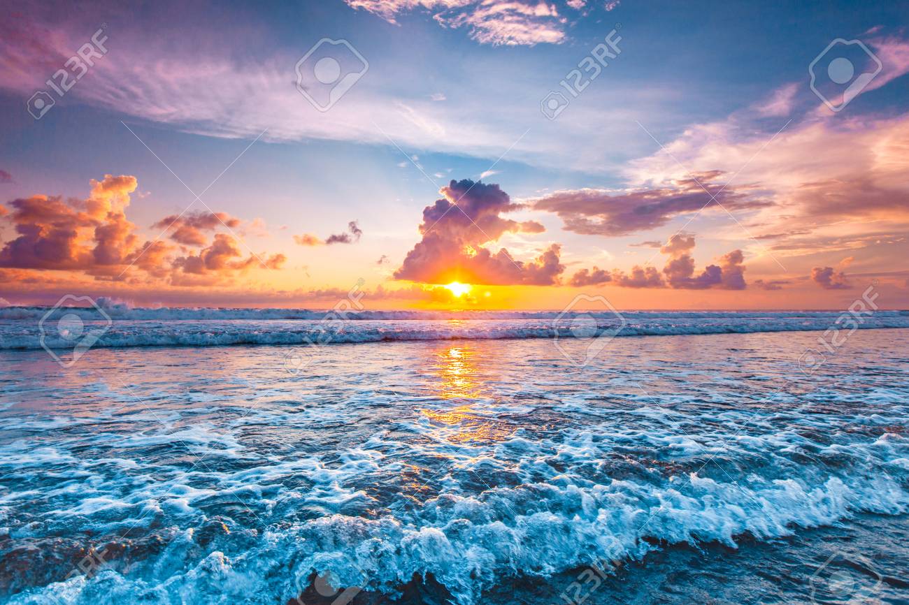 Splashing Ocean Wave In Front Of Beautiful Sunset Sky Background
