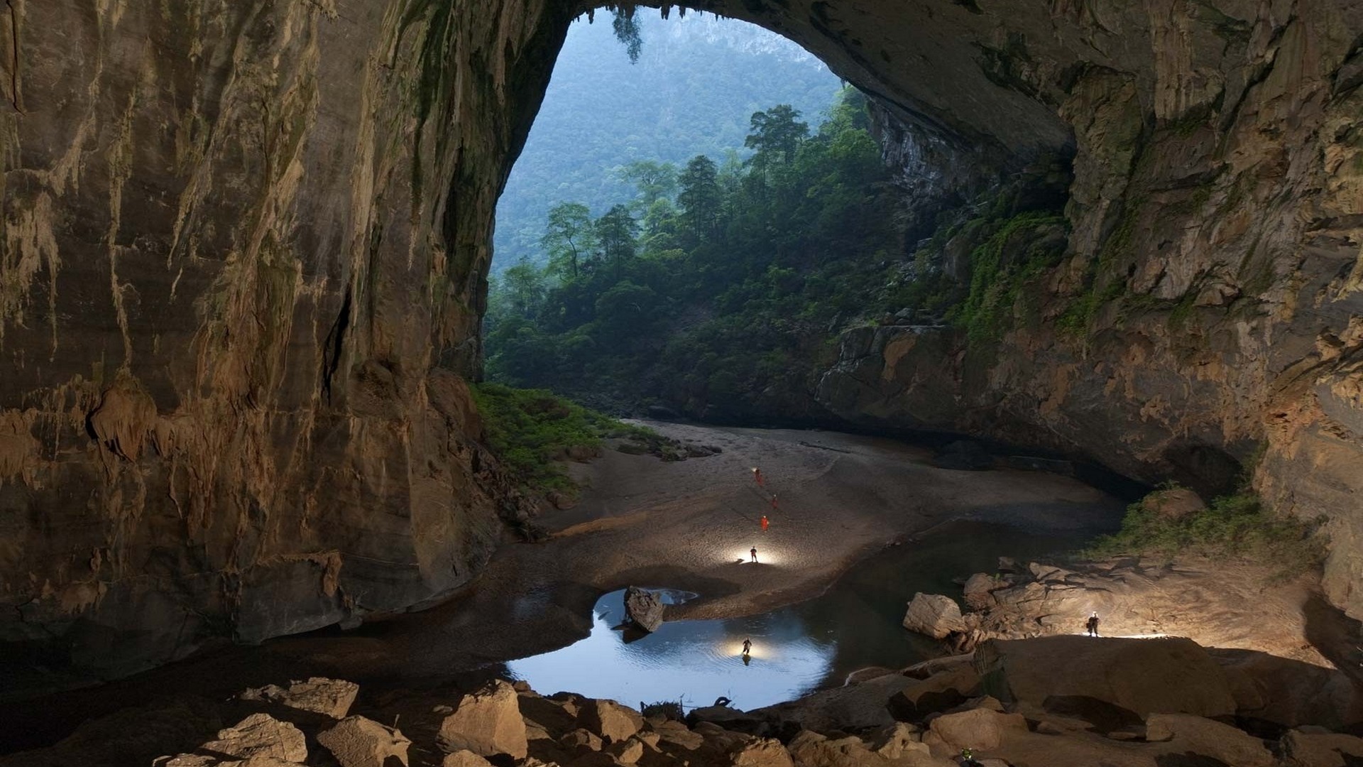 Vast cave opening with lush vegetation and explorers inside, cave wallpapers