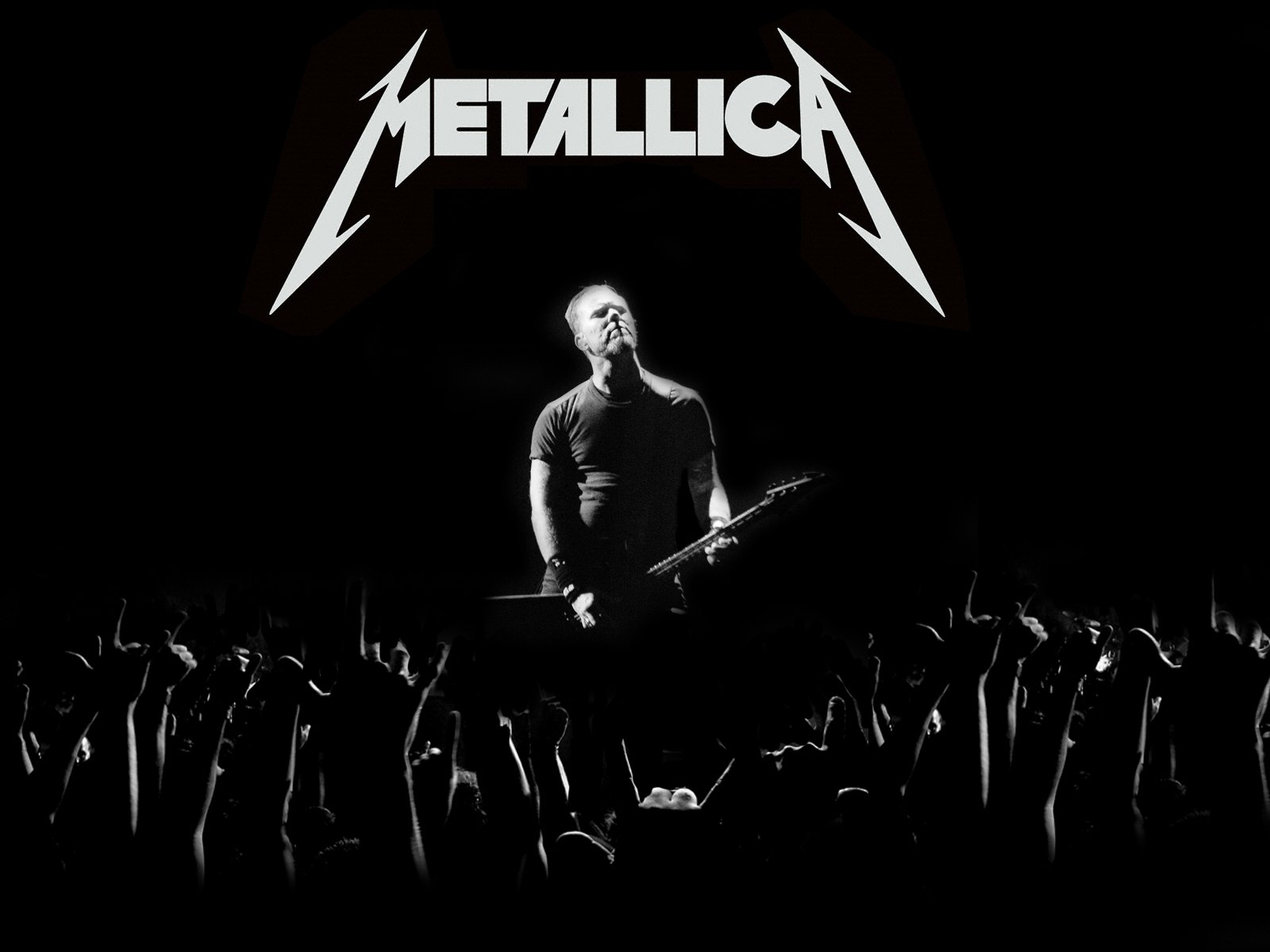 James Hetfield of Metallica performing live on stage in front of a cheering crowd, illuminated in black and white