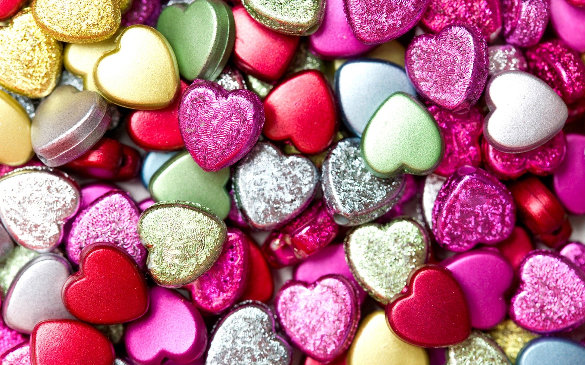 A close-up view of a pile of colorful heart-shaped beads, creating a vibrant and romantic background