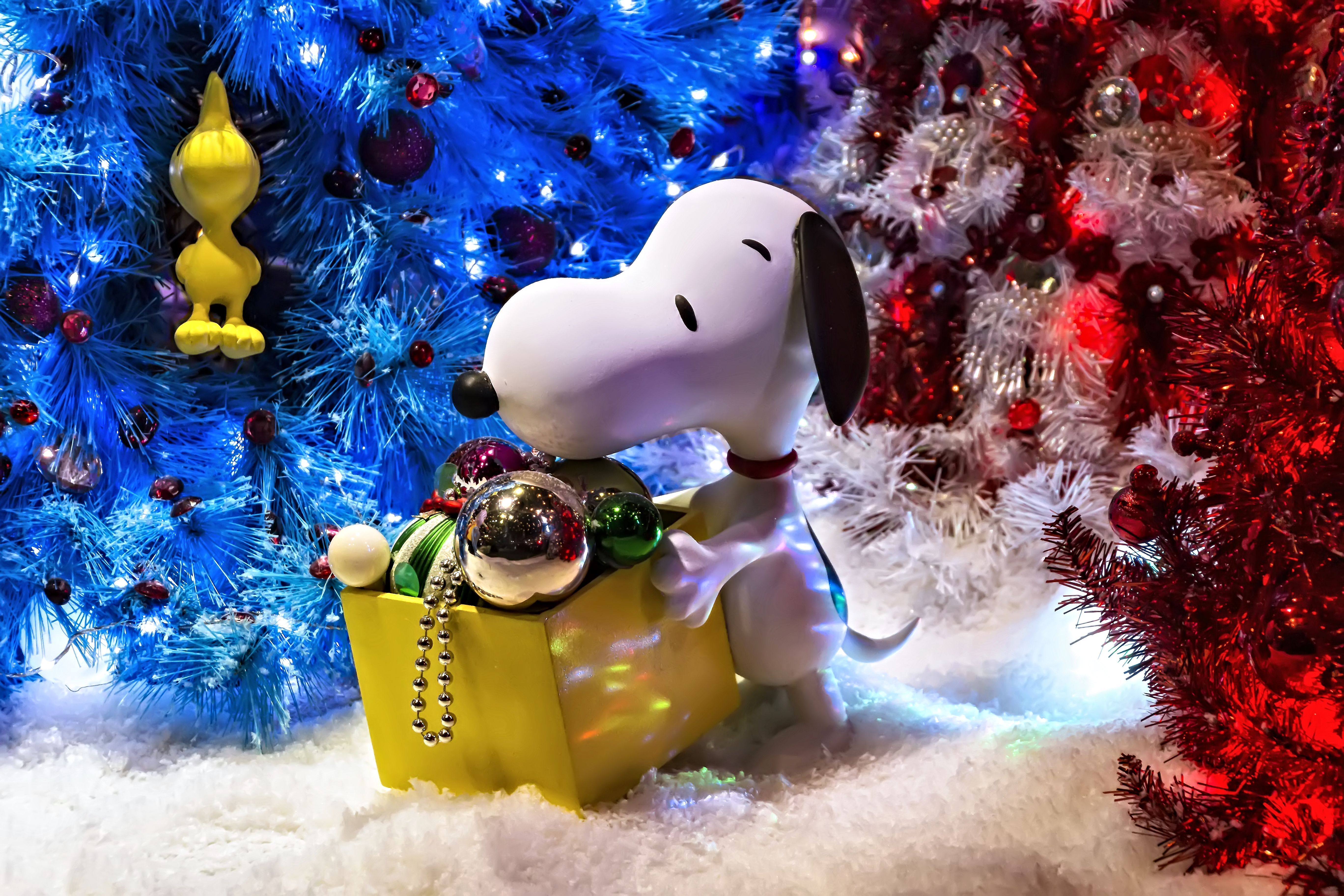 Snoopy Carrying Christmas Ornaments in Front of Christmas Trees