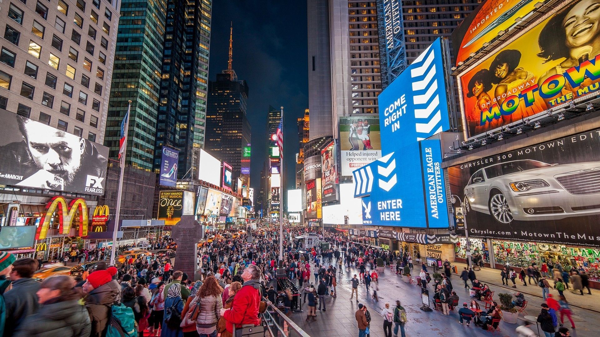 A vibrant night view of Times Square in New York City, showcasing its iconic billboards, bustling crowds, and illuminated buildings, a quintessential Broadway experience