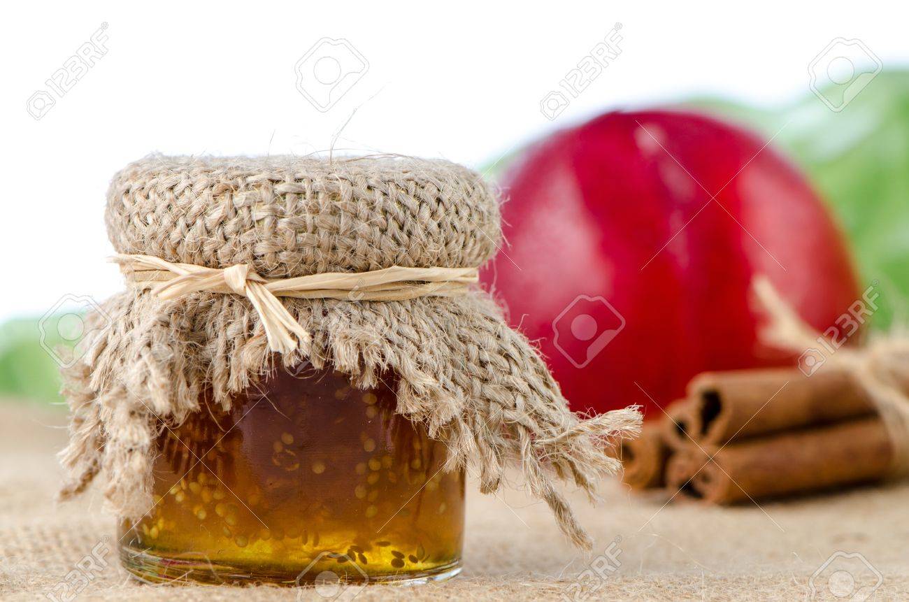 Peach Jam With Fruit And Cinnamon Over Raffia On White Background