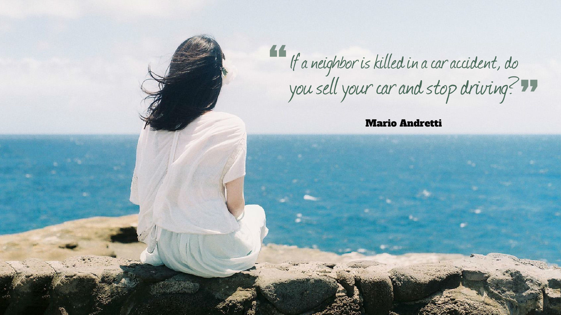 A woman contemplates a quote about car accidents by Mario Andretti, overlooking a serene ocean