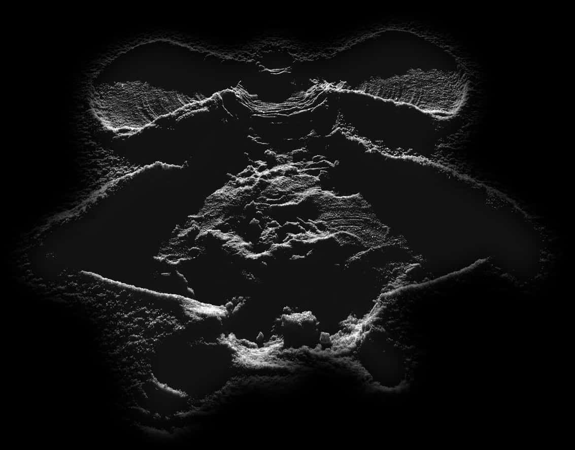 A monochromatic close-up of a snow angel, captured at night. The delicate details of the snow's texture and the imprinted form of the angel are highlighted against the dark backdrop