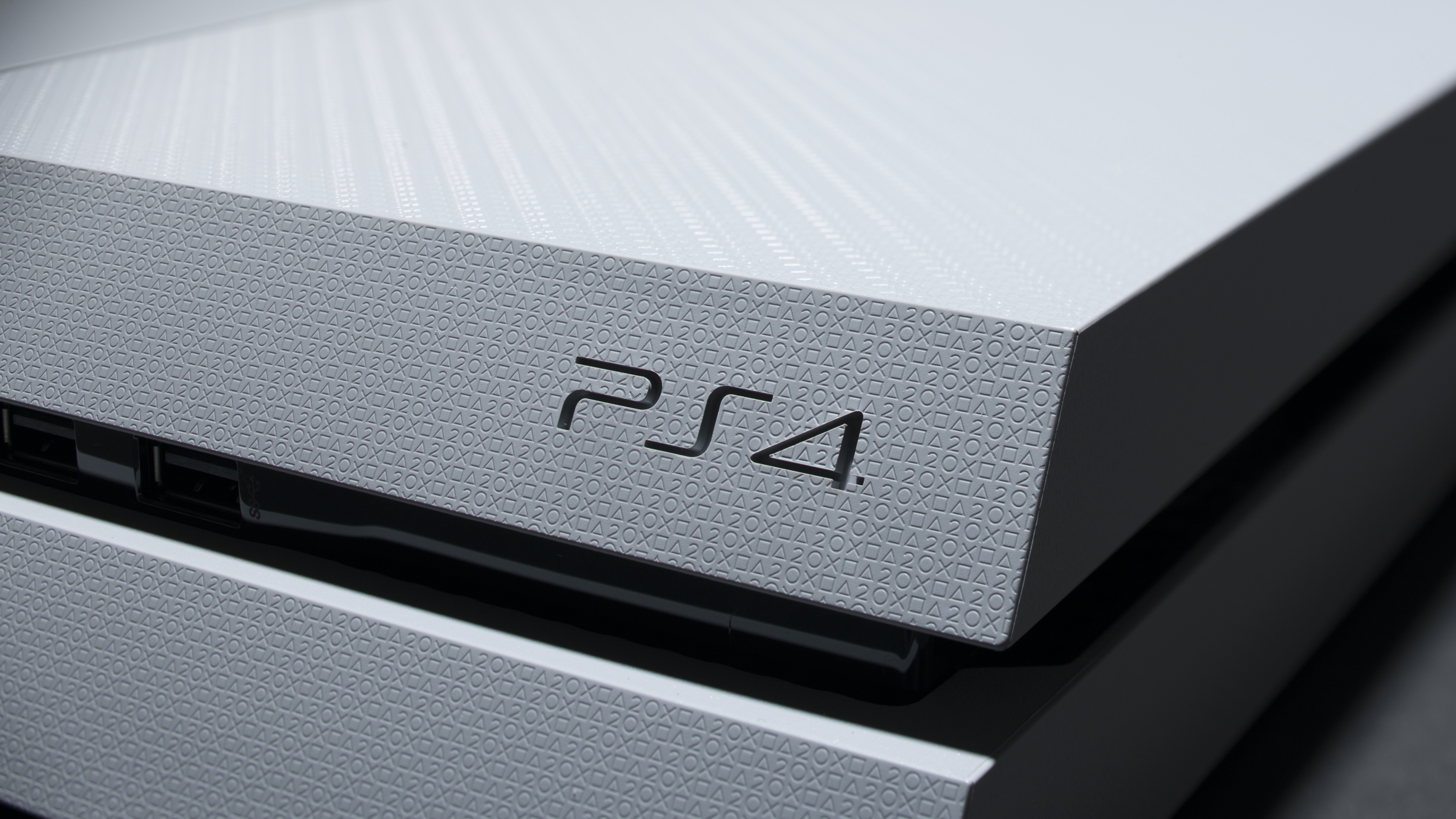 Close-up of a white PlayStation 4 console, highlighting the embossed PS4 logo and subtle geometric pattern