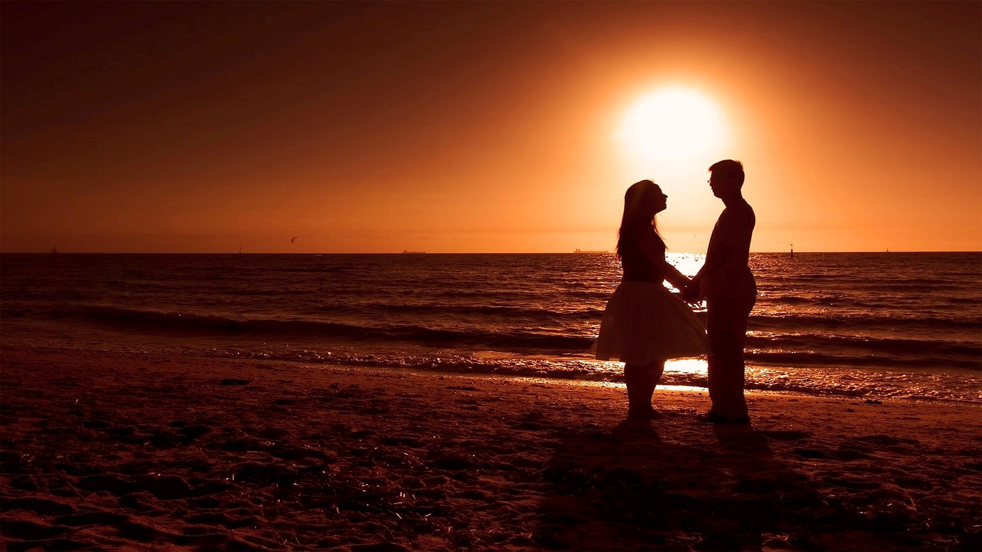 Silhouette of a couple holding hands on a beach at sunset