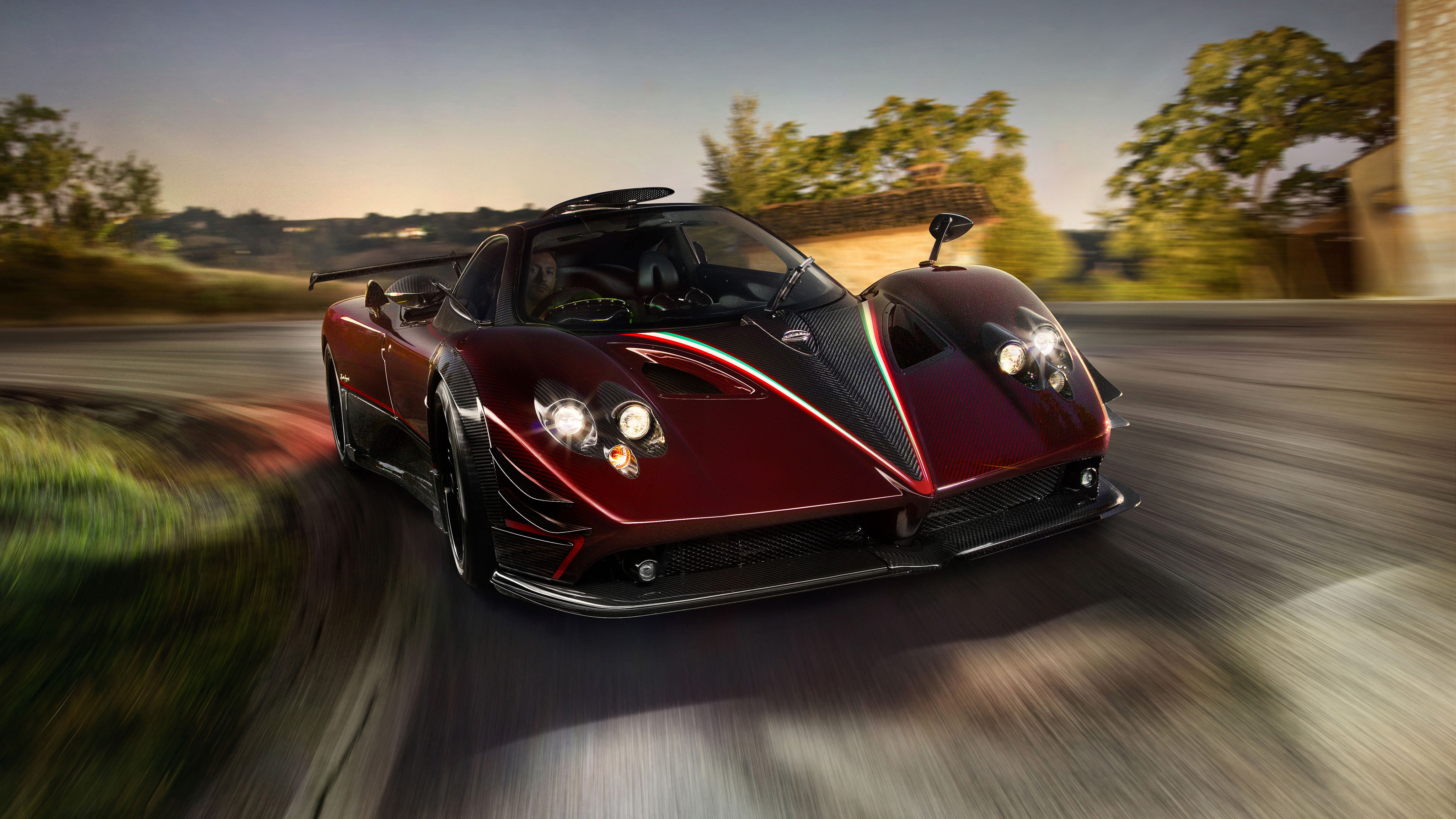 A Pagani Huayra supercar speeding down a scenic road at dusk