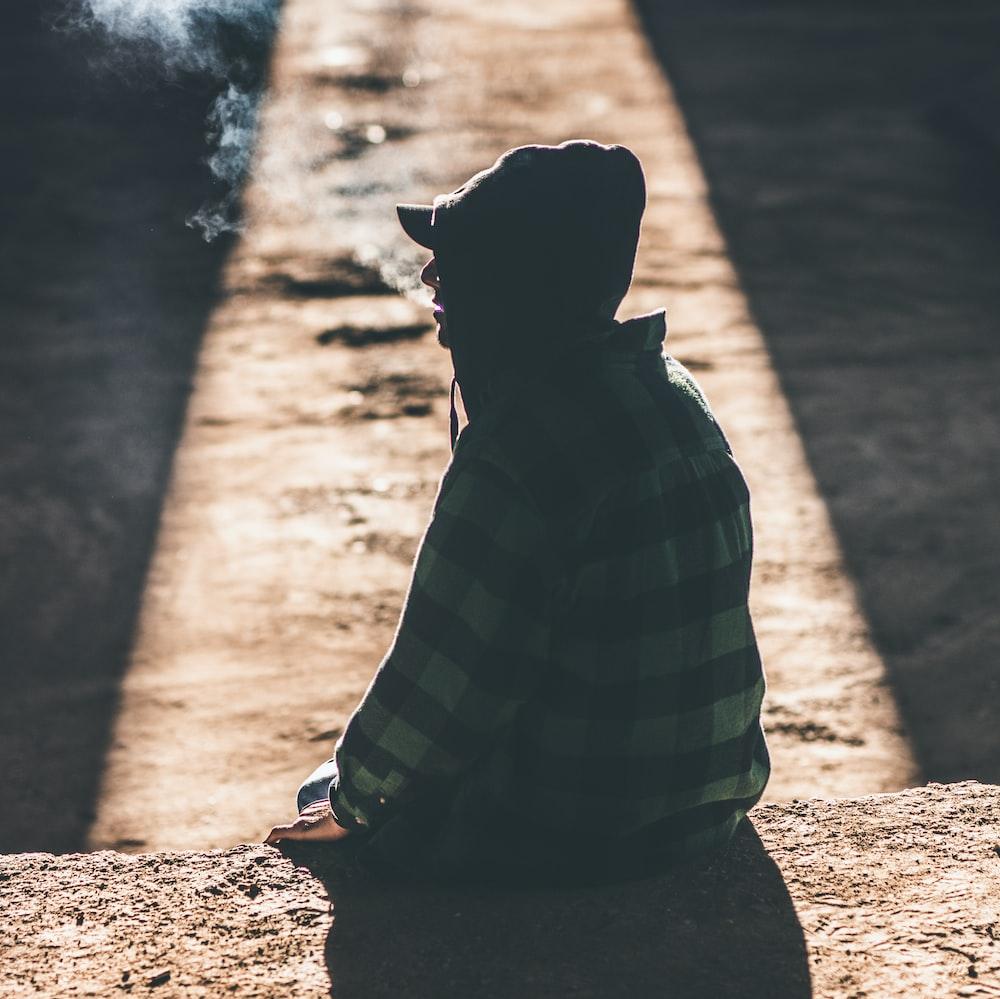 A Person Sitting On The Ground Smoking Cigarette Photo