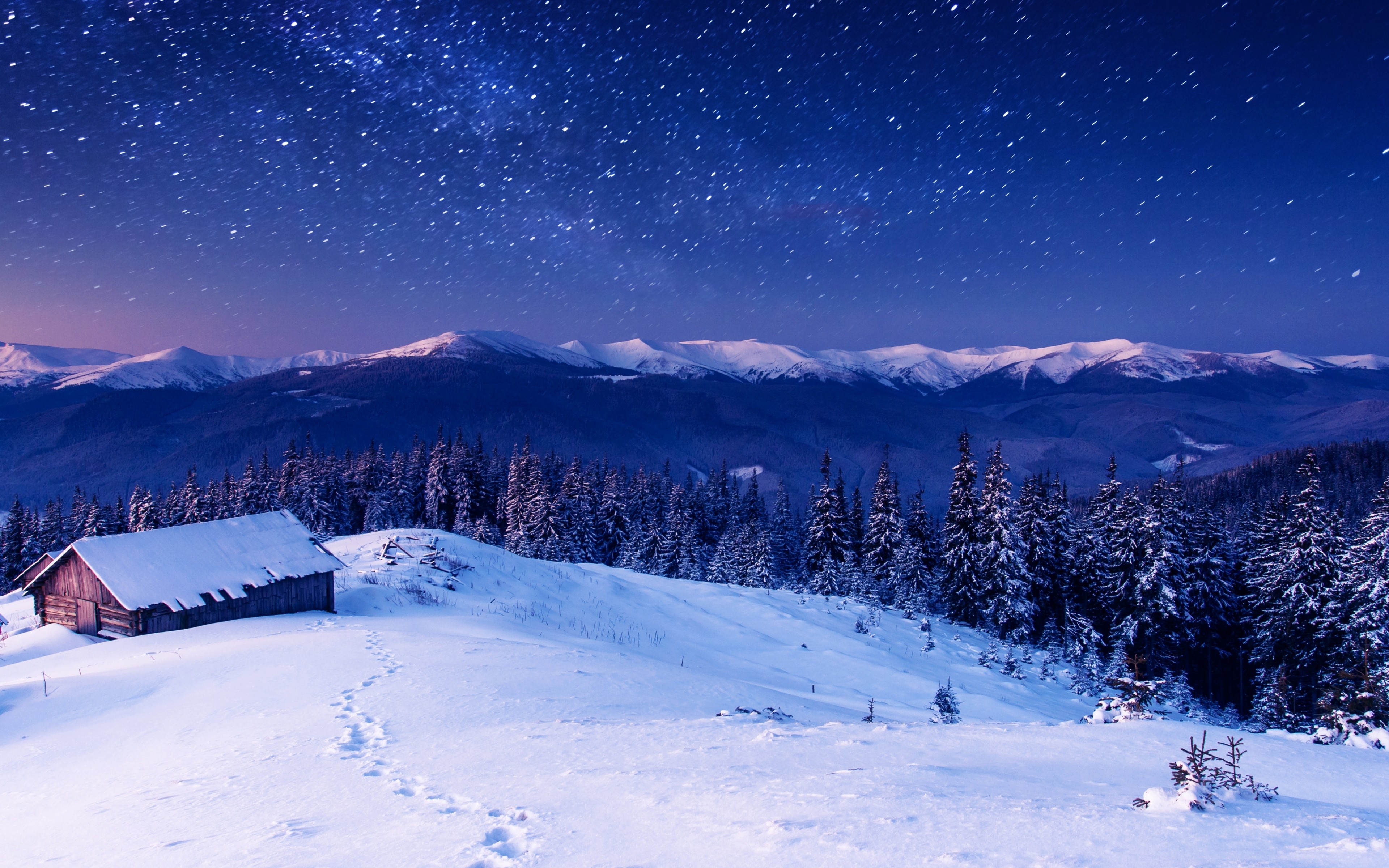 A breathtaking 4k winter wallpaper featuring a snow-covered cabin nestled in a mountain landscape under a starry night sky