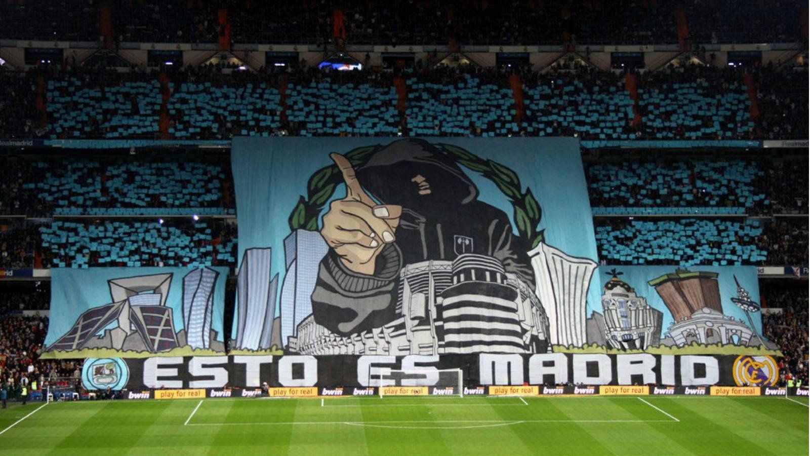 A giant tifo displayed by Real Madrid fans in the Santiago Bernabéu Stadium, featuring a hooded figure and the Madrid skyline