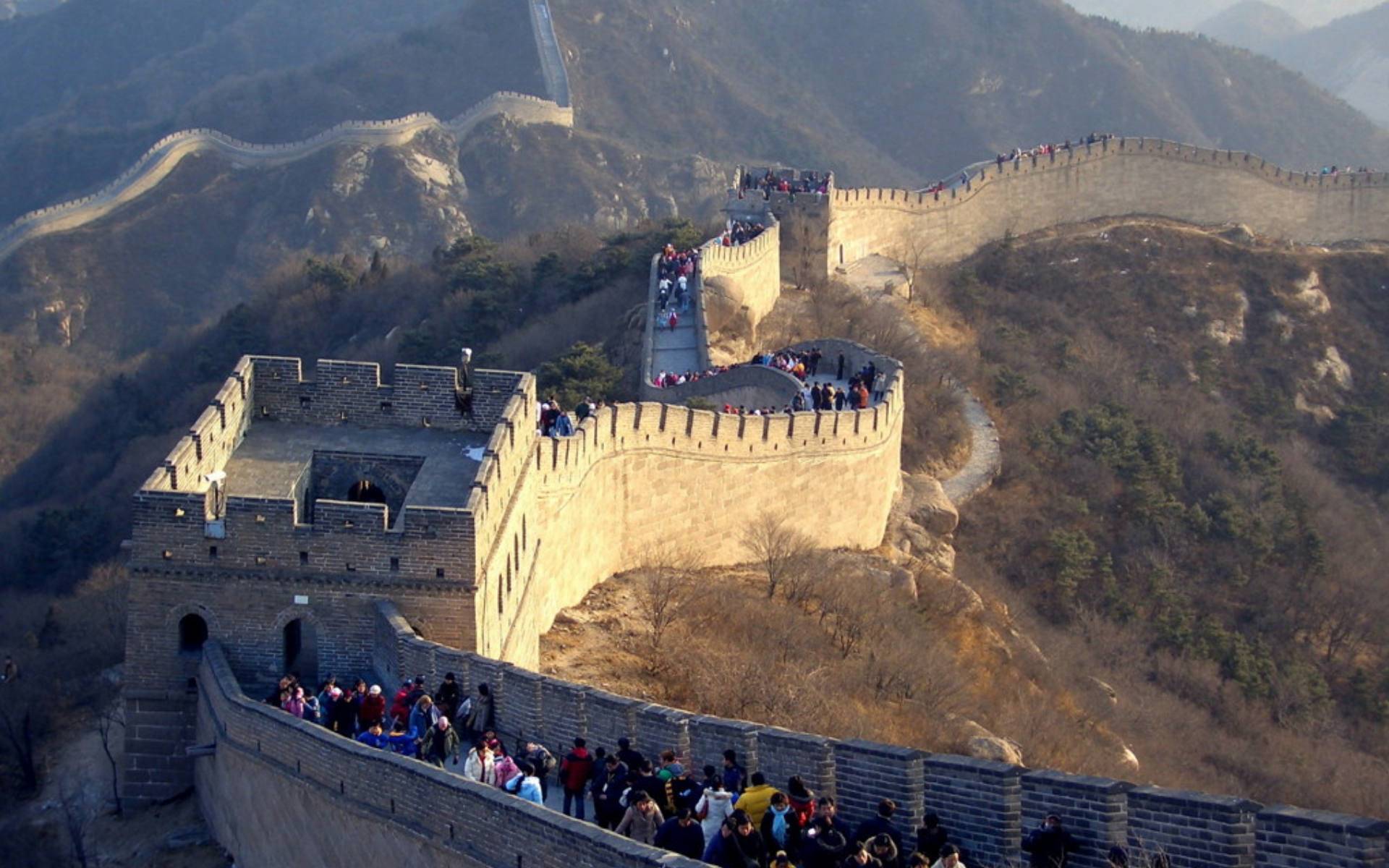 Crowds of tourists walk along the Great Wall of China, snaking its way through the mountains
