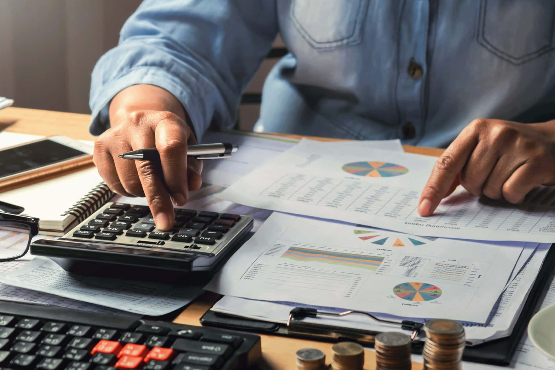 A person using a calculator and reviewing financial documents, highlighting the importance of accounting in business