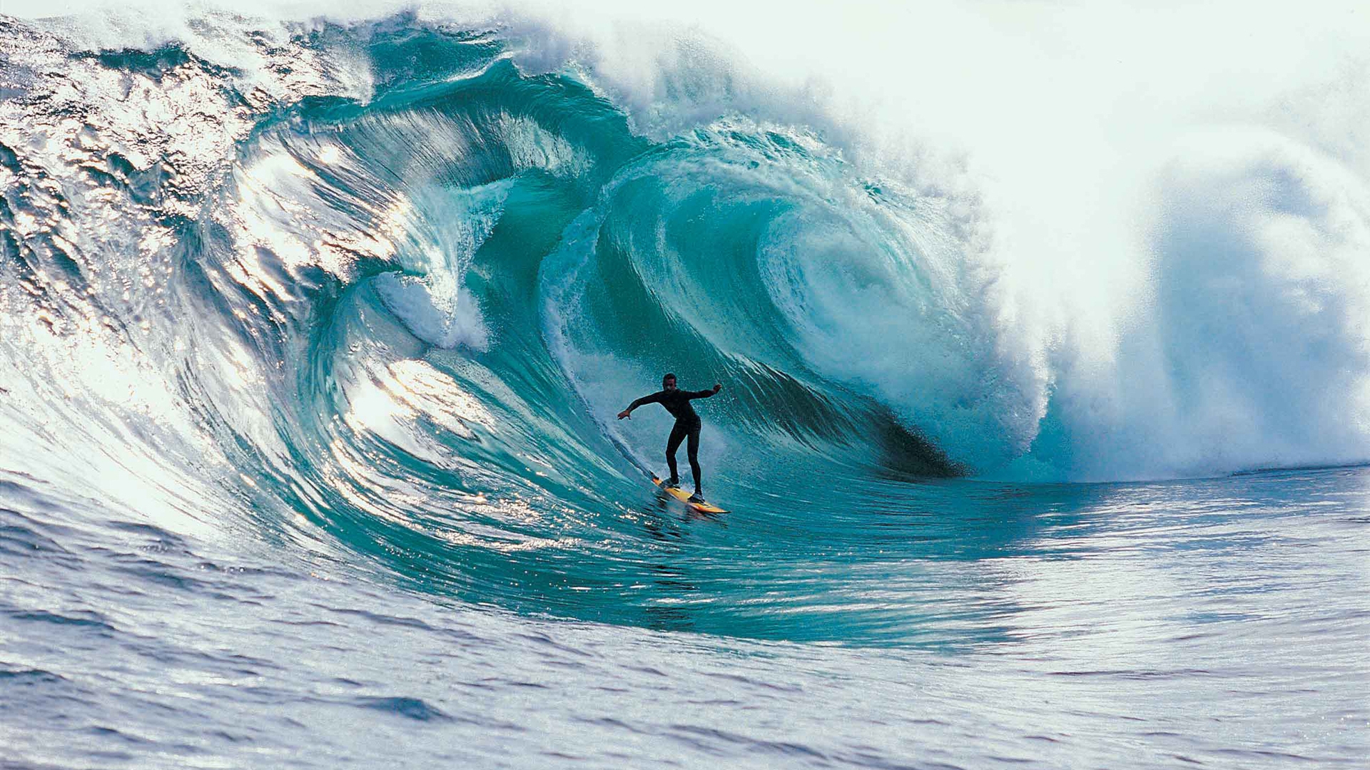 A surfer rides a massive, barreling wave in the ocean, showcasing the thrill and power of surfing