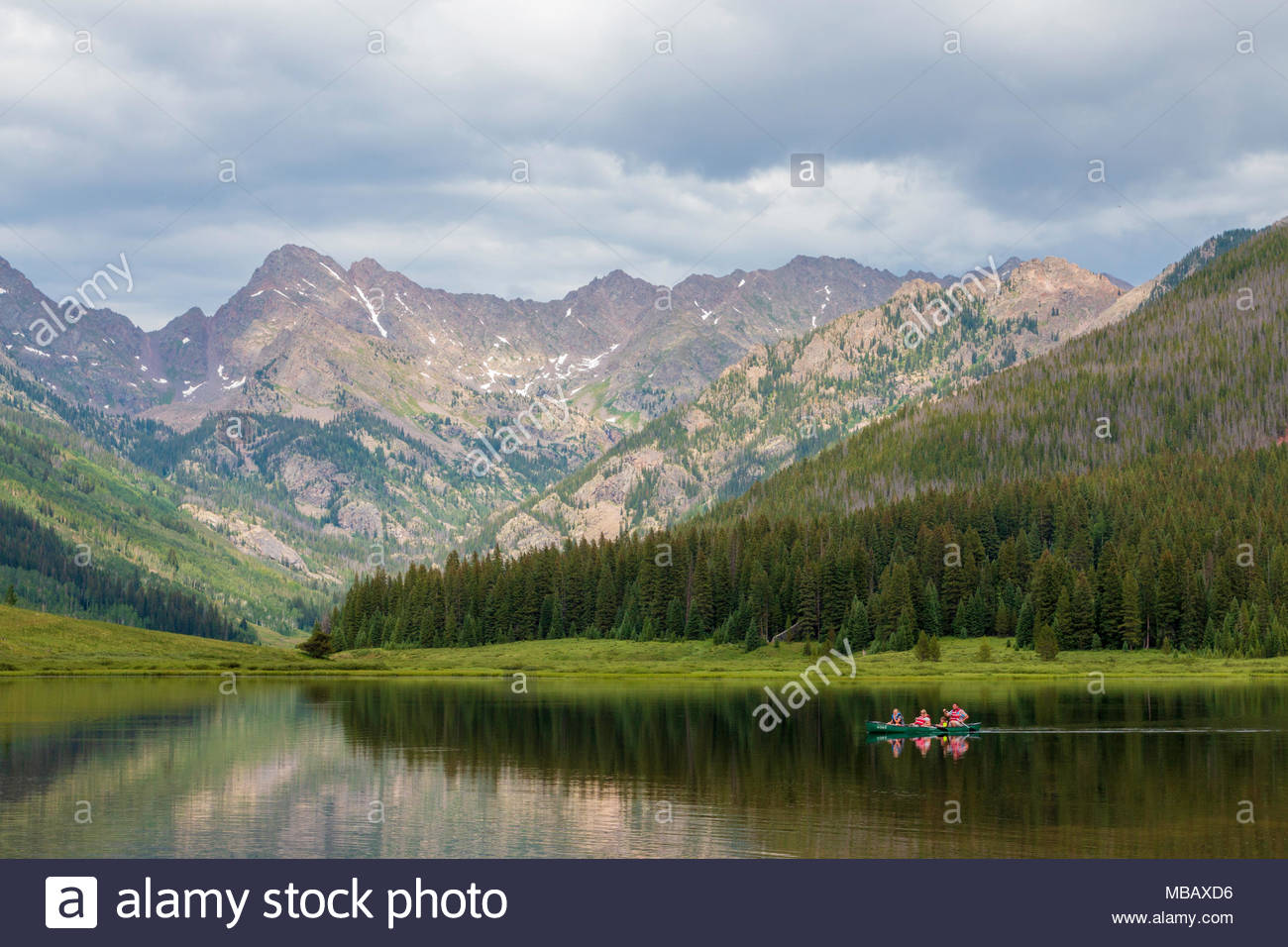 A Family Paddles Their Canoe Across Piney Lake With Mountains In