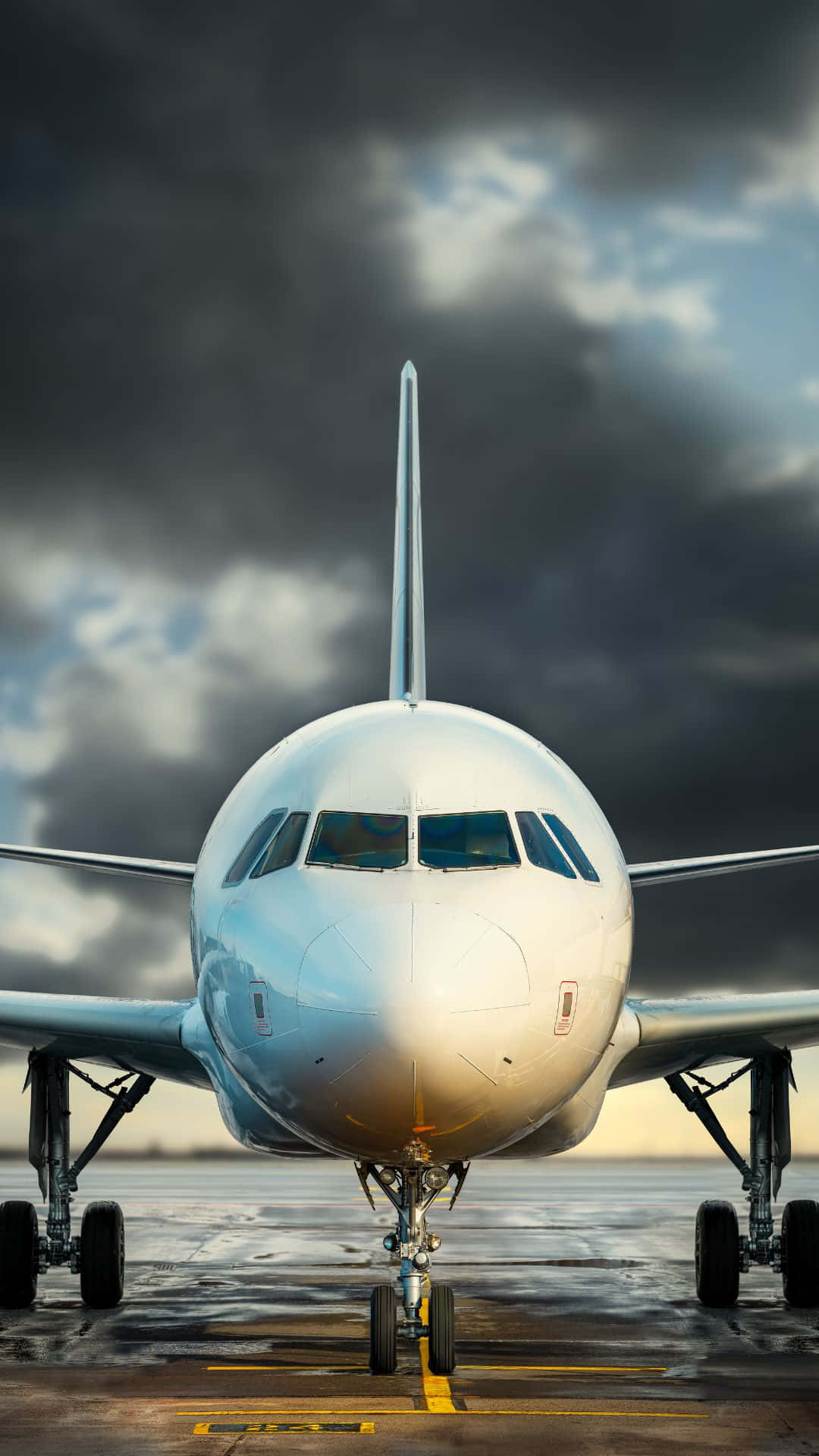A commercial airplane parked on the tarmac against a stormy sky