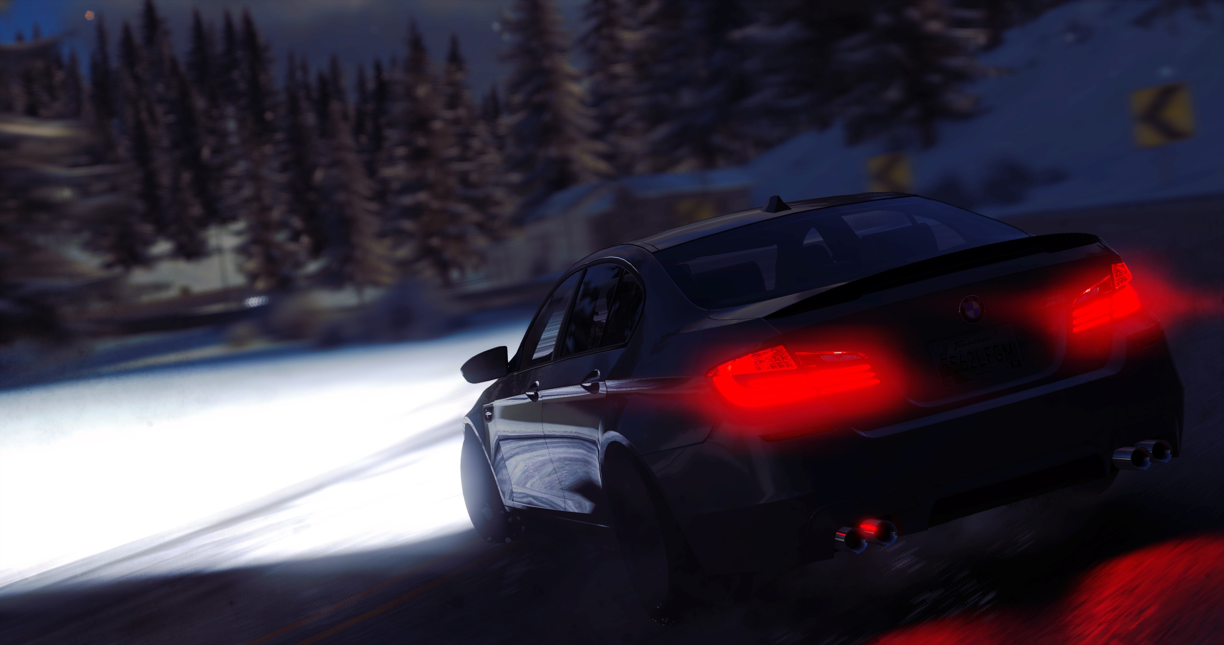 Black BMW sedan driving on a snowy road at night