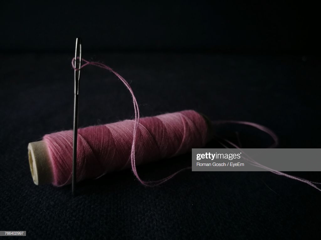 Closeup Of Thread Spool With Needle Against Black Background High
