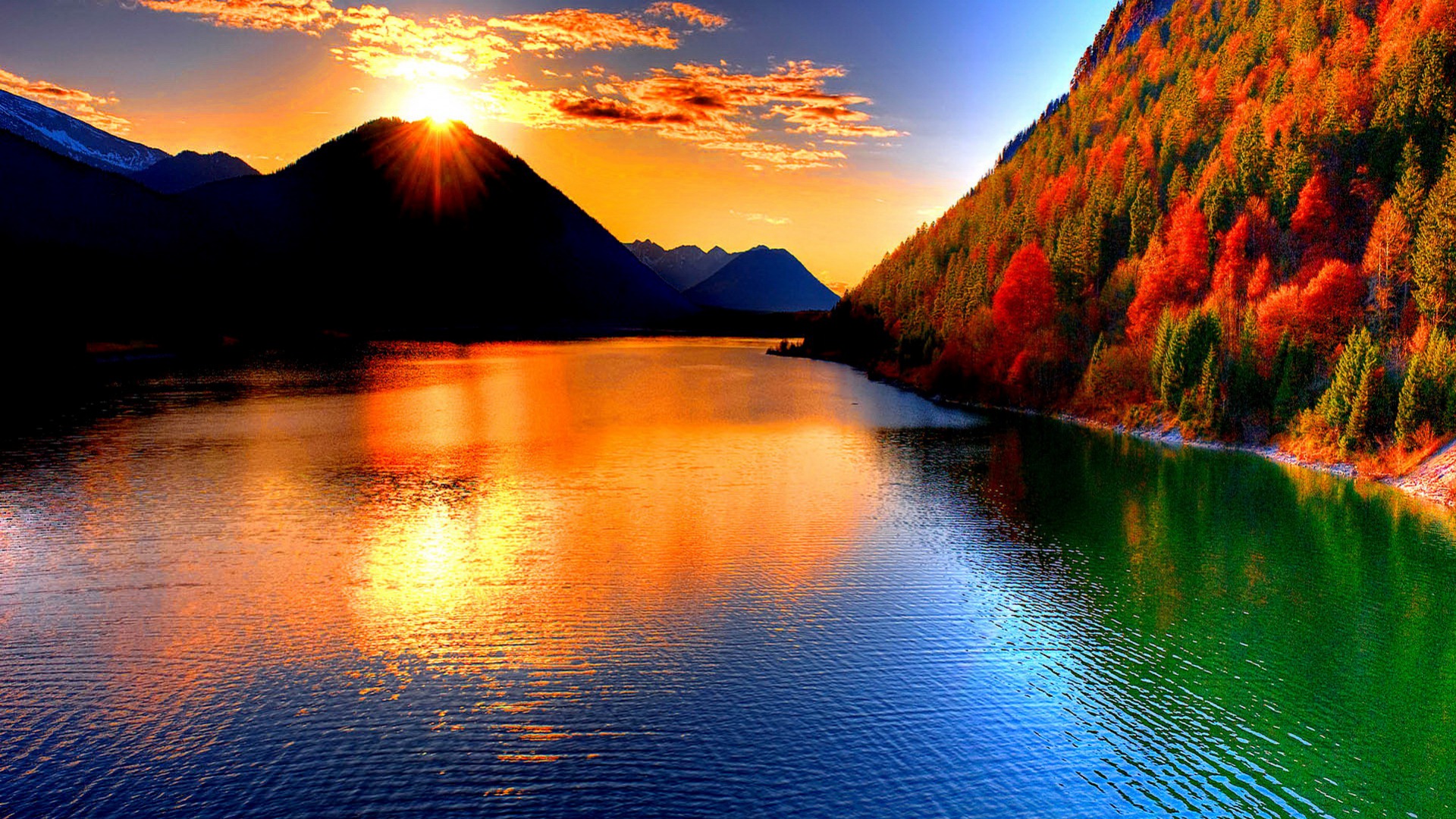 A stunning sunset over a tranquil lake, reflecting the vibrant colors of the sky and the autumn foliage on the shoreline