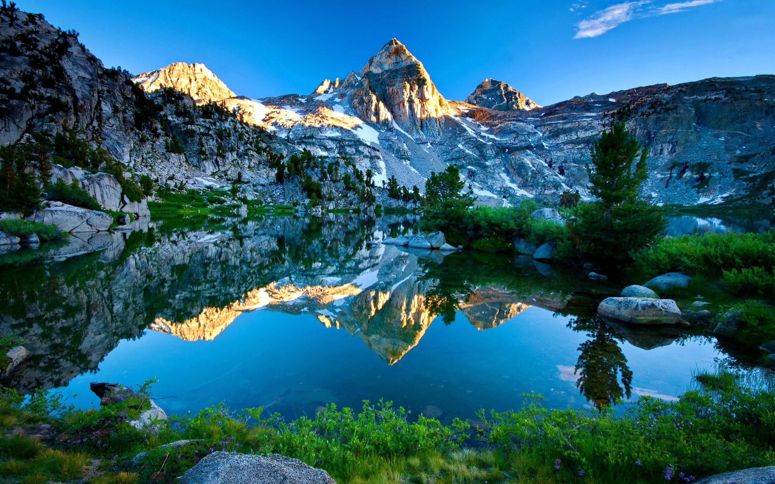 Serene mountain lake reflecting majestic peaks at sunrise