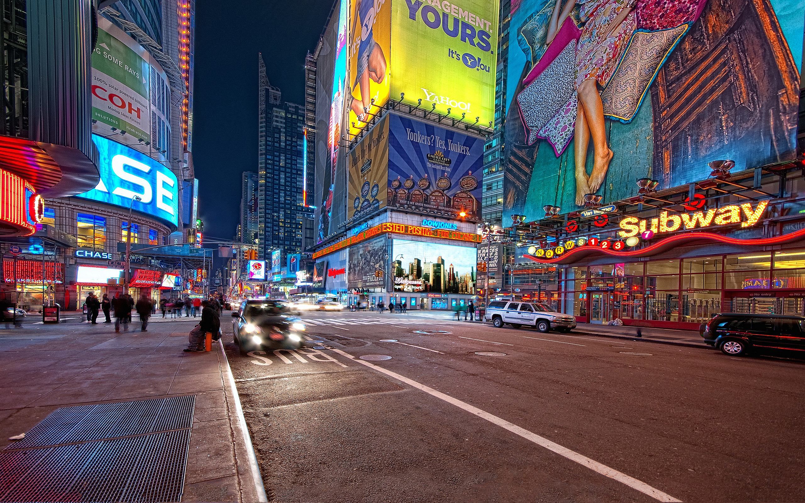 A vibrant night view of New York City's Times Square on Broadway, showcasing dazzling billboards, illuminated signs, and bustling city life