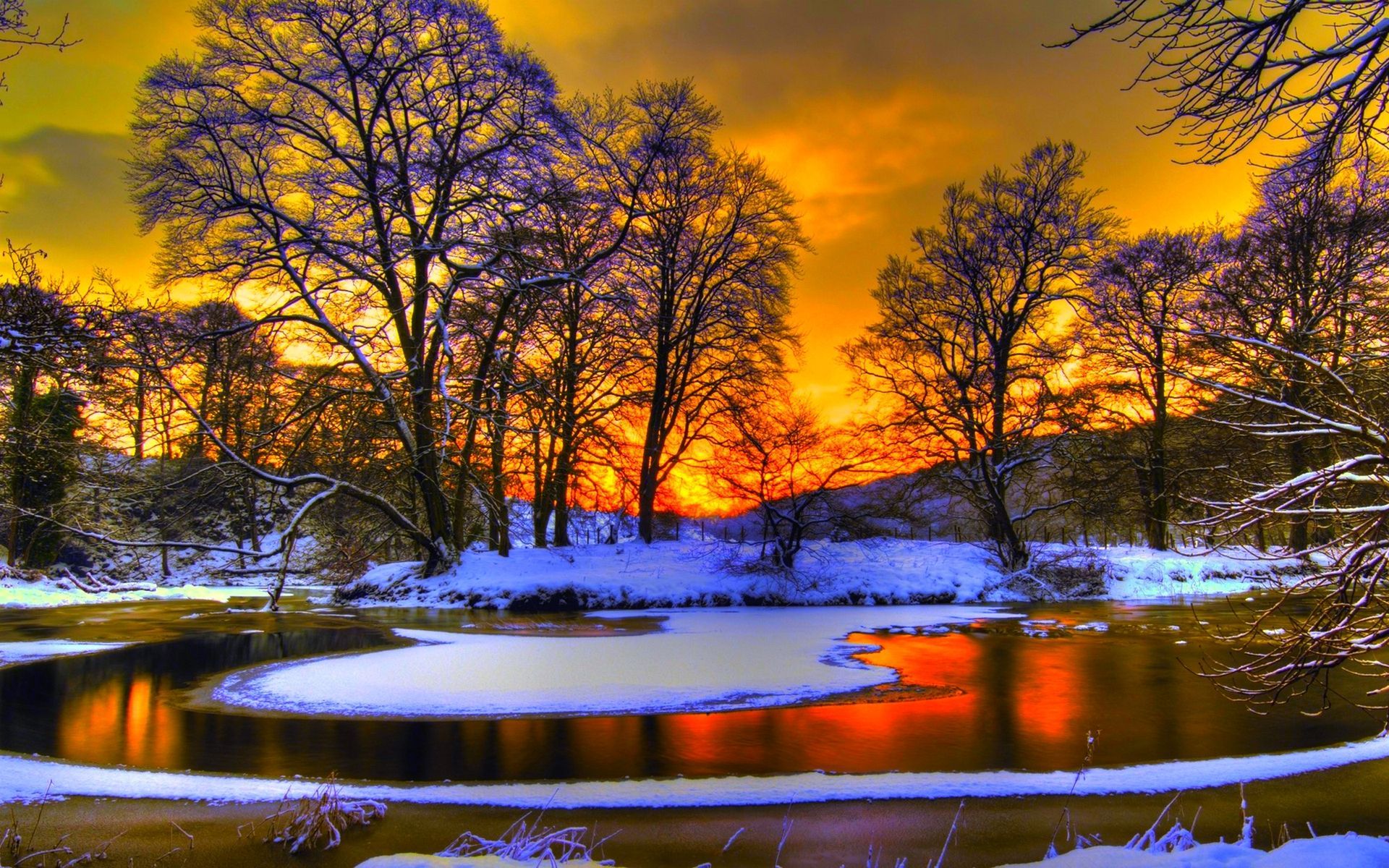 A breathtaking winter sunset reflected in a partially frozen river, surrounded by snow-covered trees and banks