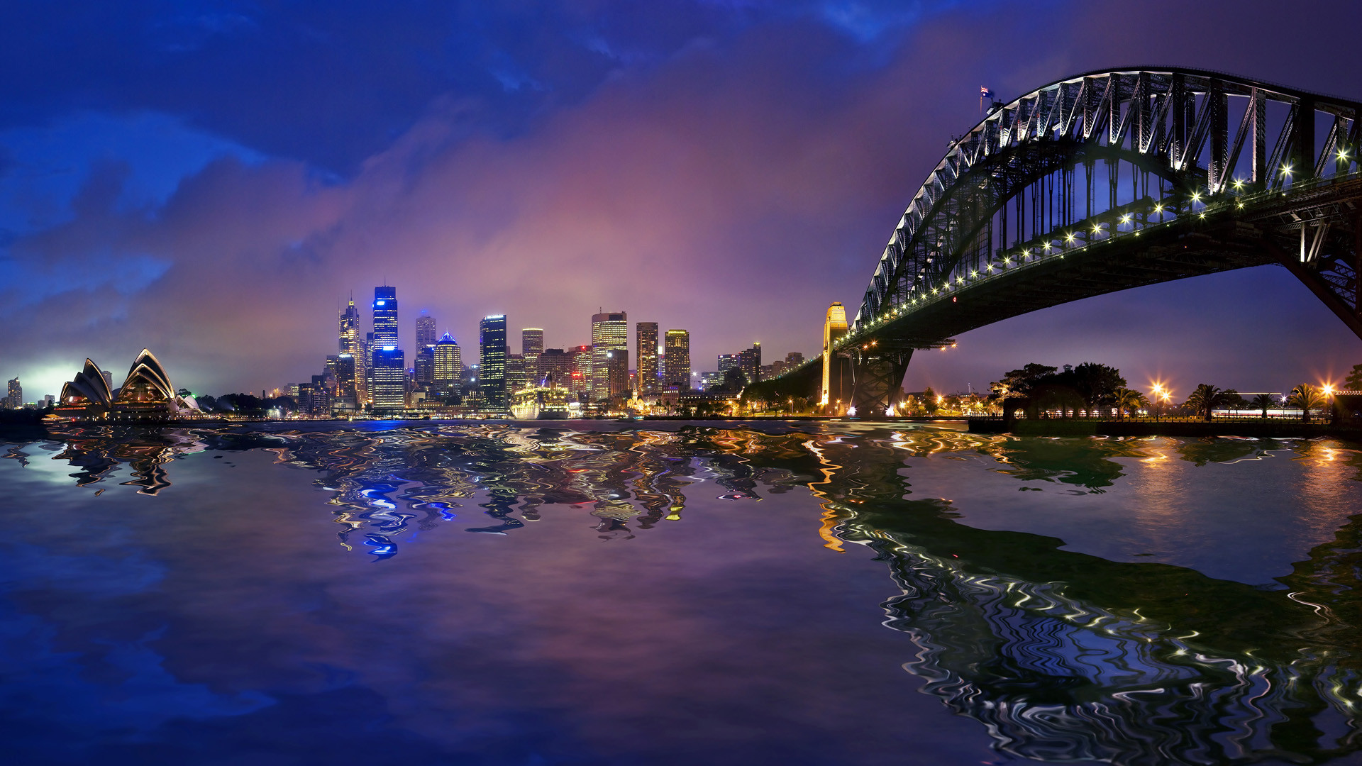 Sydney Harbour at night with the Sydney Opera House and Harbour Bridge reflected in the water